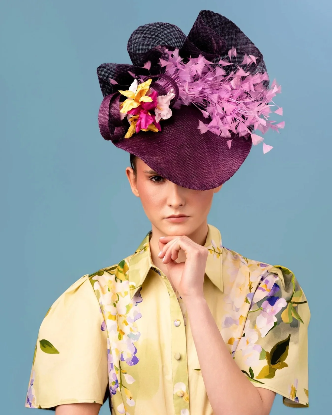 One of our signature silhouettes, defined by structure, movement, and precision.

Sculpted from fine sinamay straw, this headpiece frames the face with intention while a windowpane swirl rises with architectural clarity. 

Feather accents soften the 