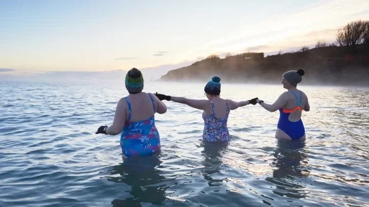 Women swimming in the cold sea showing solidarity and community