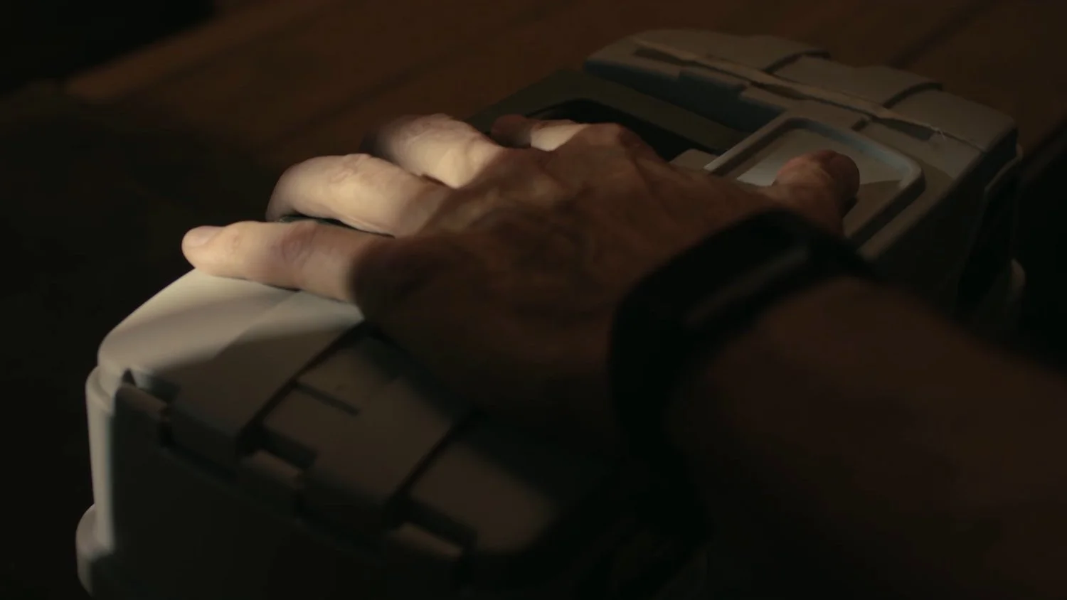 A hand pressing buttons on a device with a small display screen.