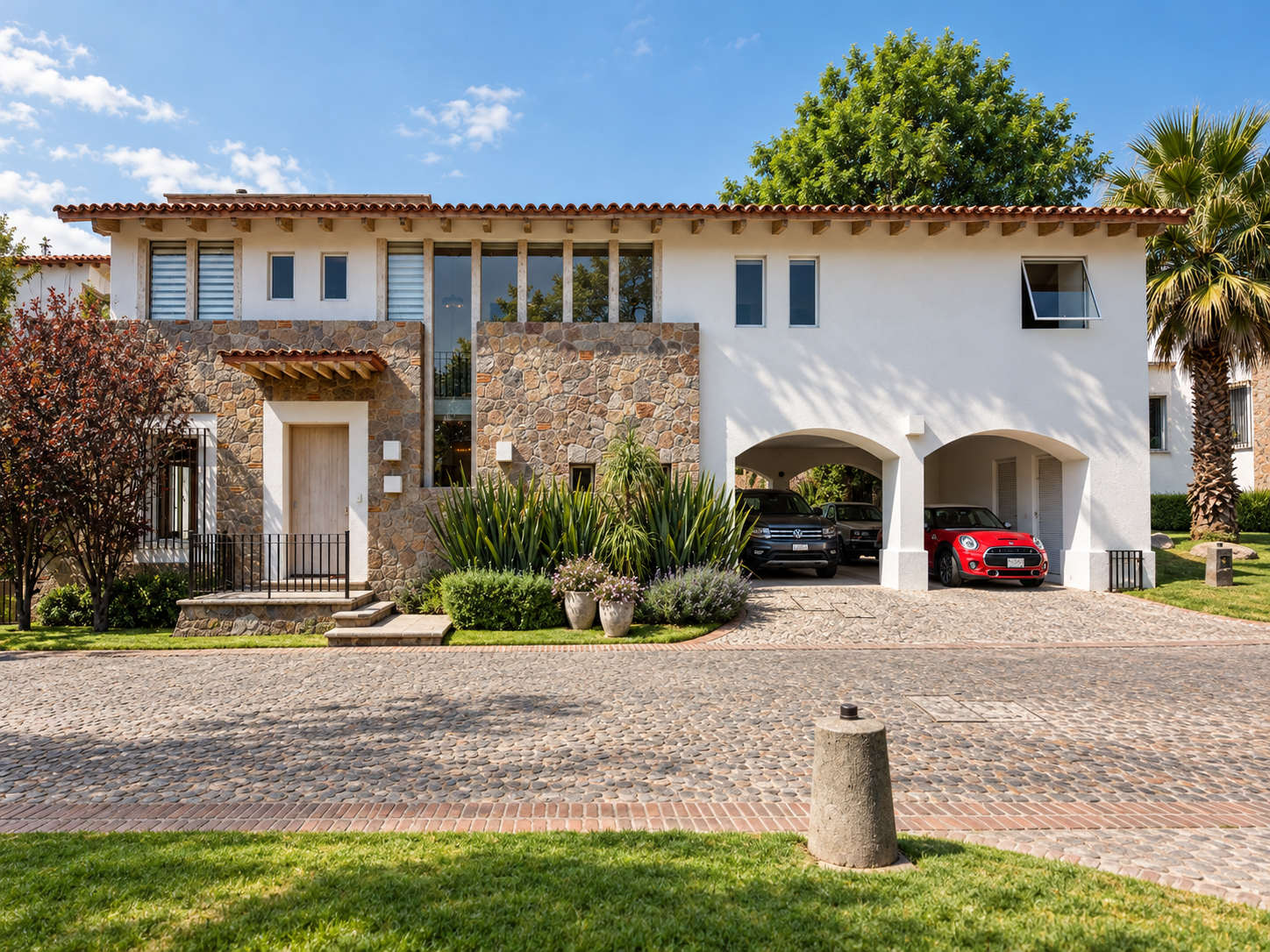 Fachada principal de Rancho San Bartolo con recubrimiento de piedra, cubierta de teja y jardín frontal.