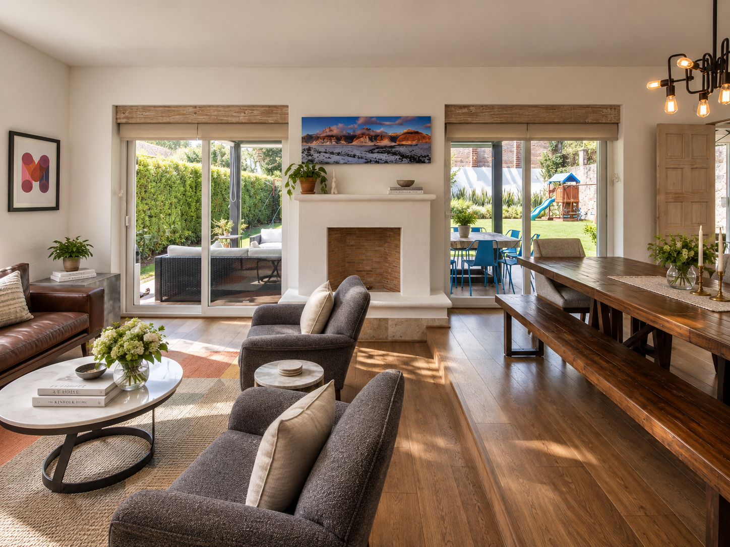 Sala de Rancho San Bartolo con chimenea, ventanales hacia el jardín y sillones en tonos neutros.