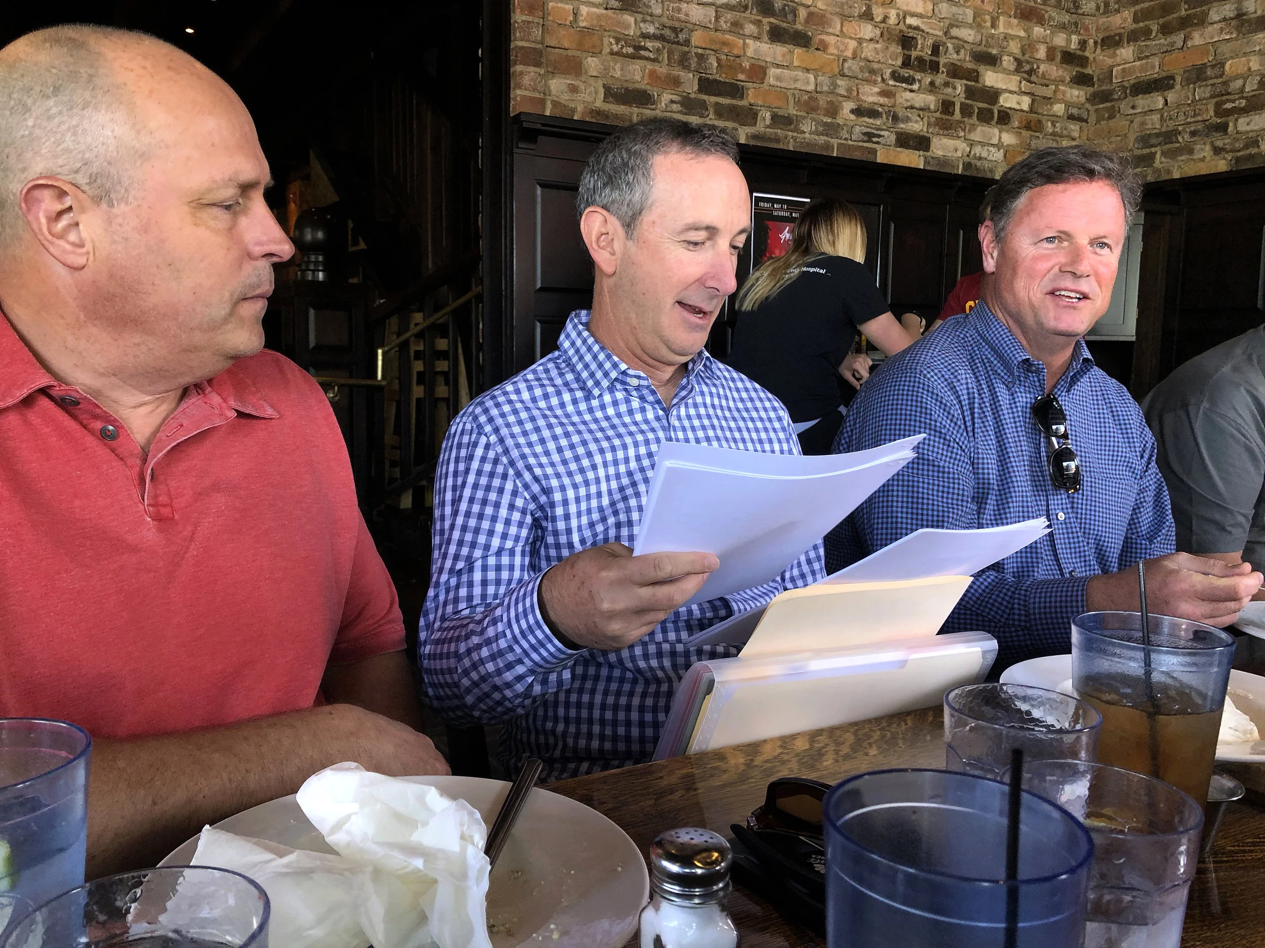 Matt Maiocco (center) sorts through letters from fans while sitting with Kirk Reynolds (left) and Lal Heneghan at lunch in Whitefish, Montana on May 20, 2018 before visiting Dwight Clark in his home.