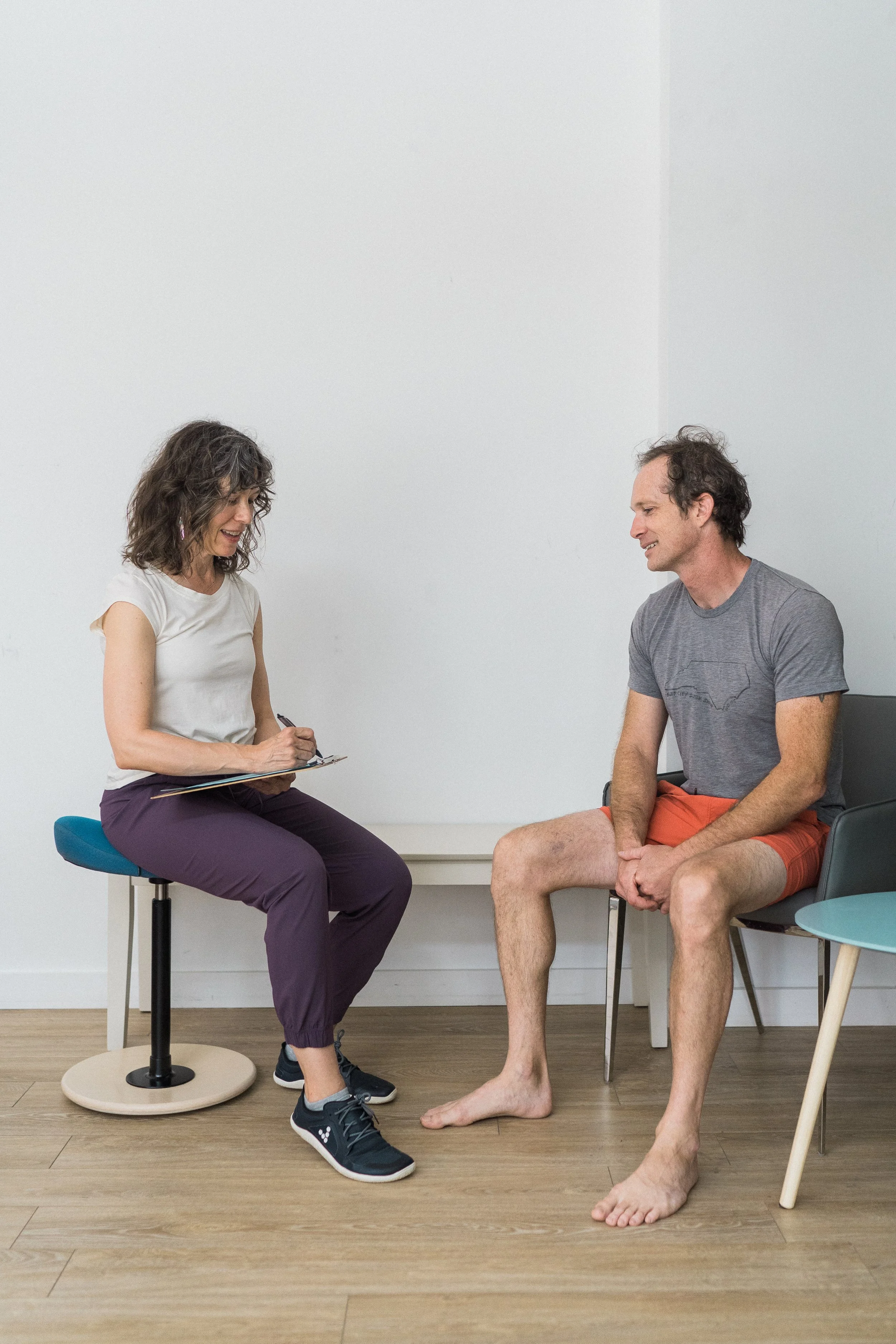 Melissa Schneider speaks with a seated client about their concerns and goals during an individual Rolfing® consultation.
