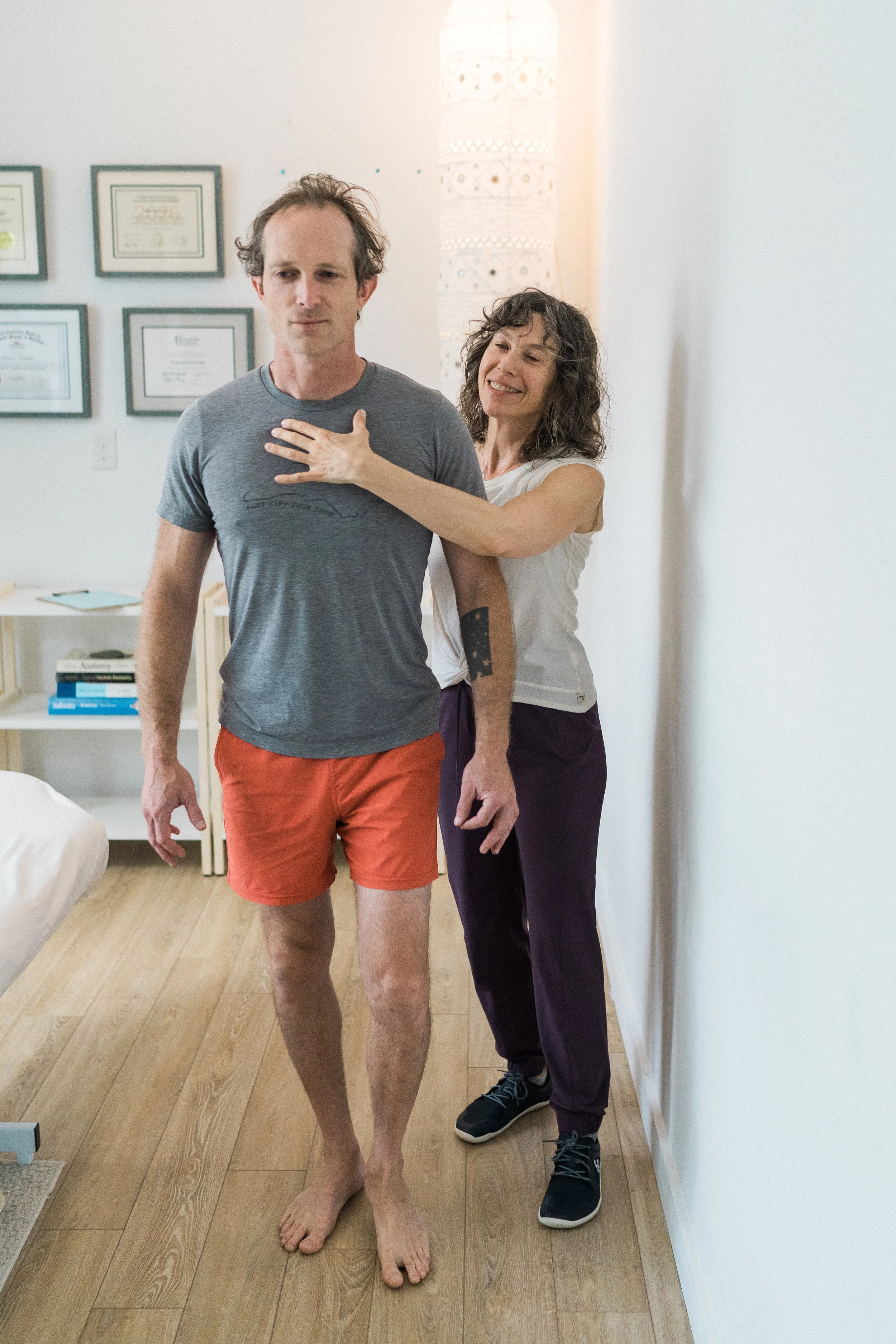 Melissa Schneider guides a standing client through postural awareness and movement exploration during a Rolfing Structural Integration session.