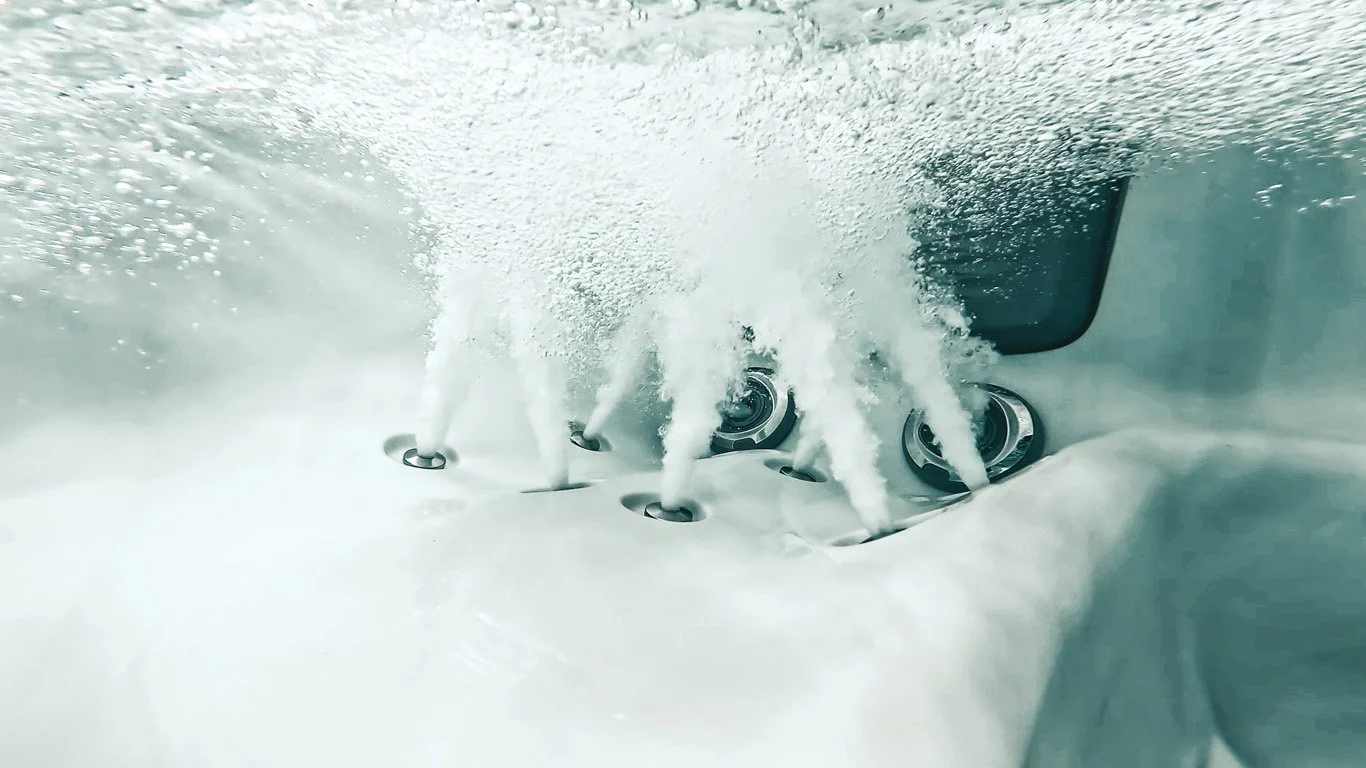 Close-up underwater view of Focus Relief® Jets releasing streams of bubbles into a light-colored tub.