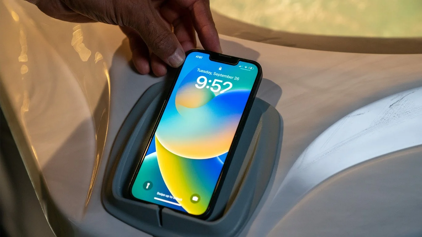 A hand places a smartphone on the tub edge holder, ready to enjoy an Entertainment Package from the lock screen.