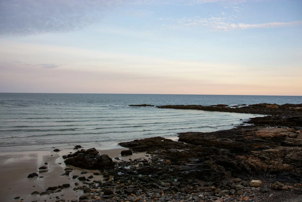 Calm ocean with gentle waves and rocks along the Maine shoreline