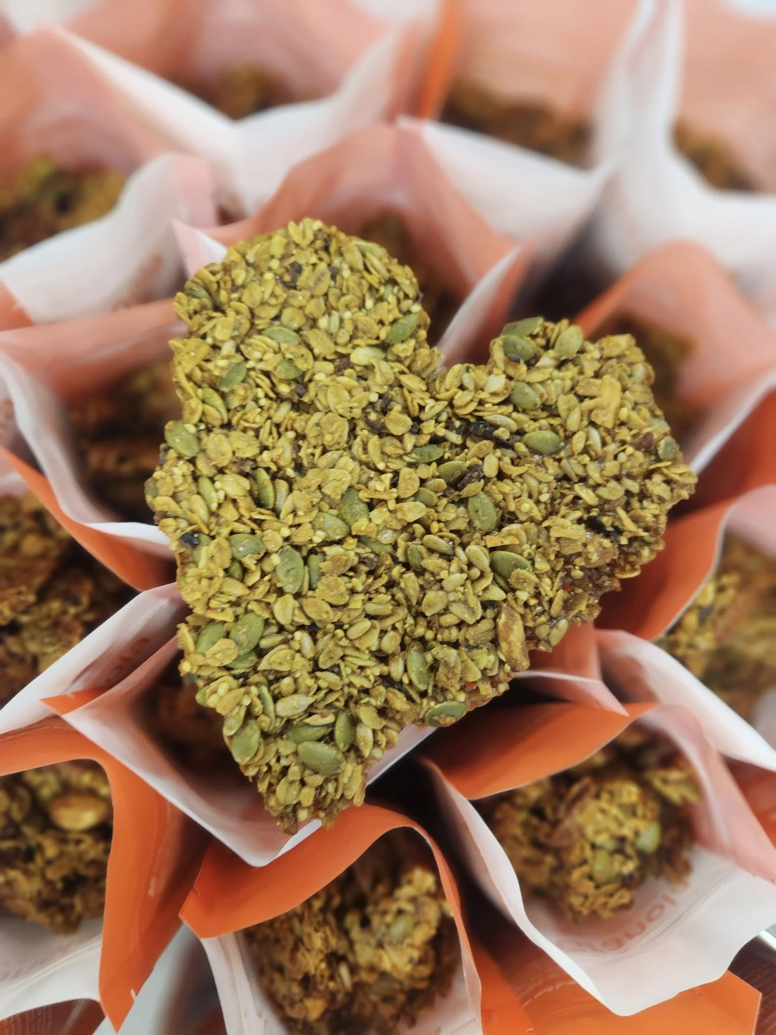 Close-up of granola bars made with nuts and seeds, wrapped in orange and white packaging.