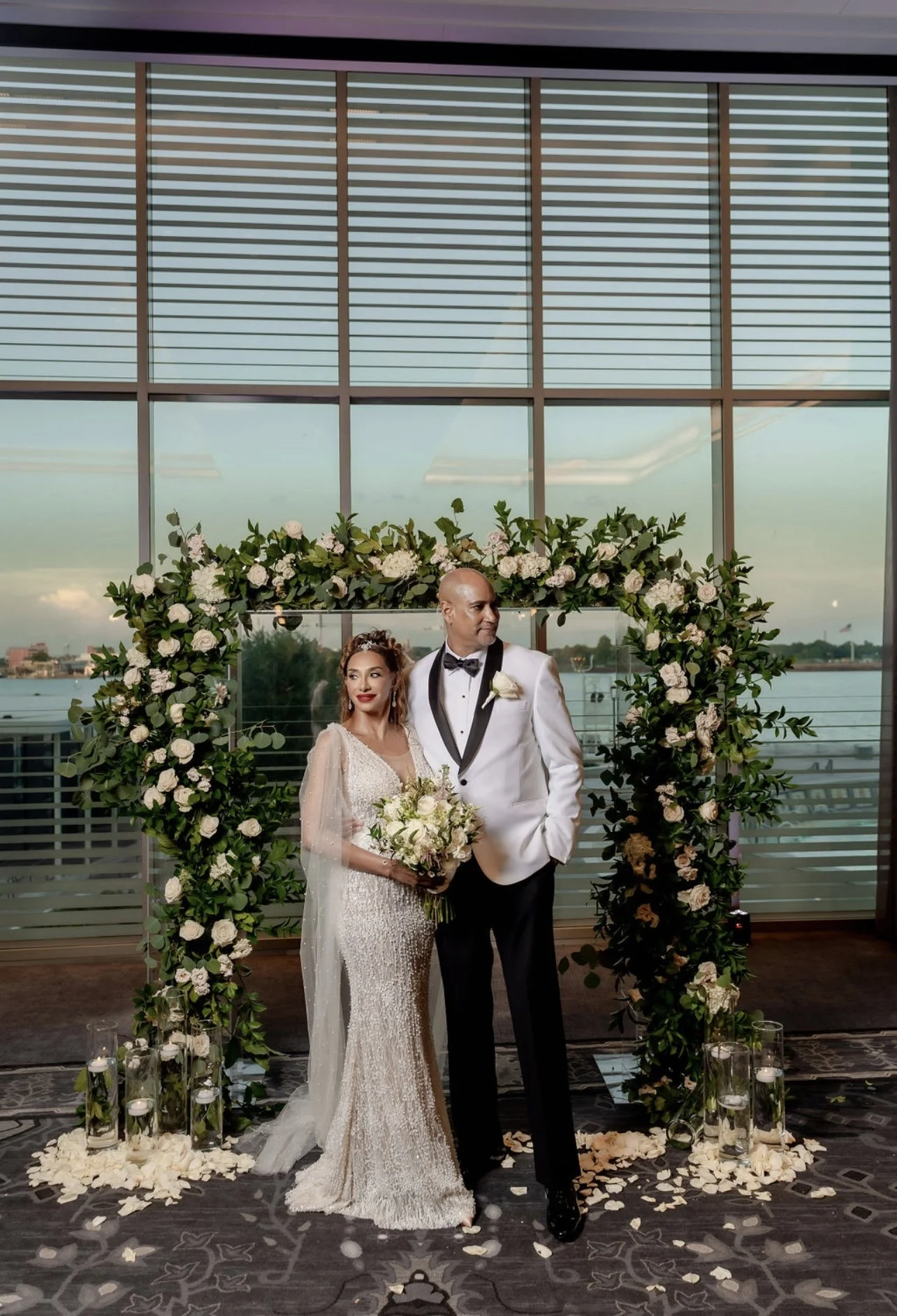 Bride and groom at an intimate New Orleans wedding ceremony featuring a floral arch, candle decor and waterfront views.