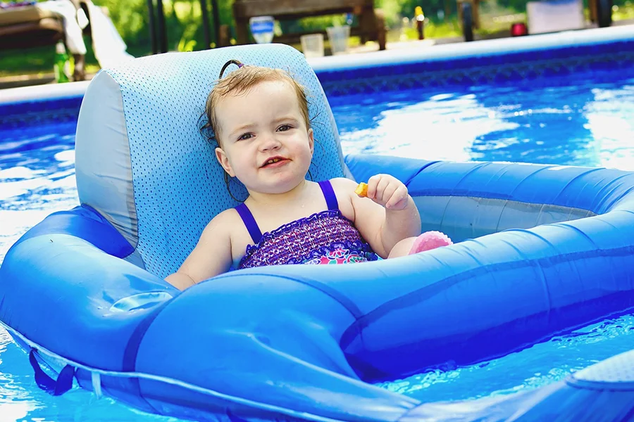 little baby eating a snack on a pool raft