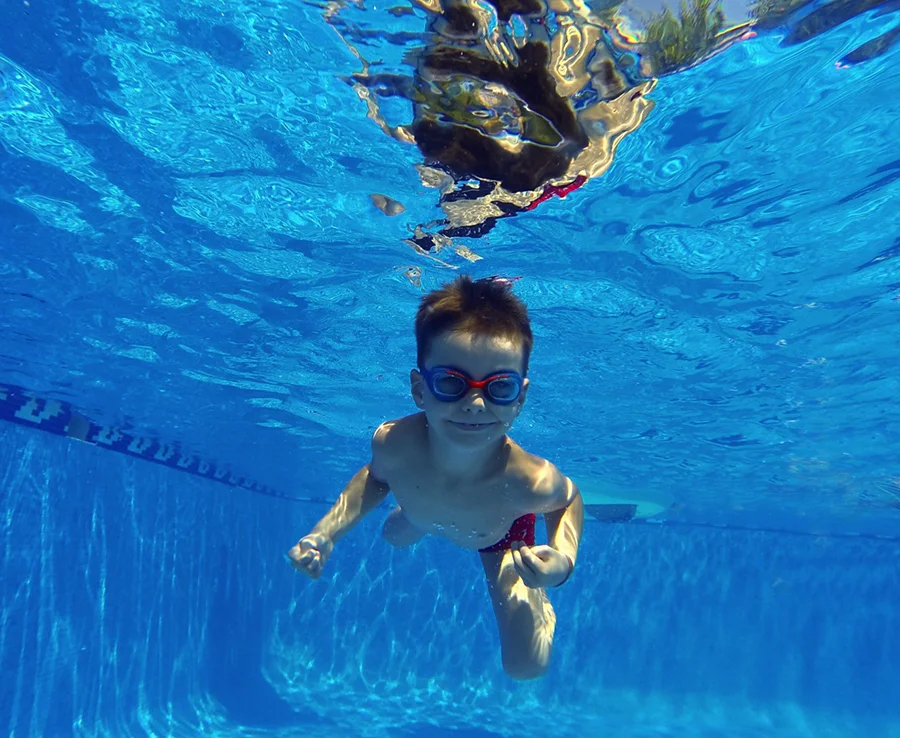 little boy swimming underwater in pool