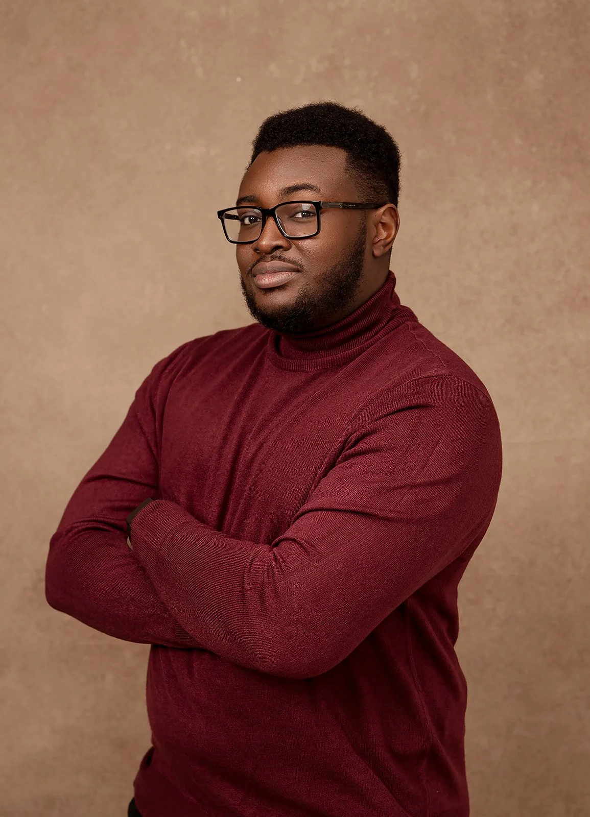 Author Kevin Obike wearing glasses and a burgundy sweater