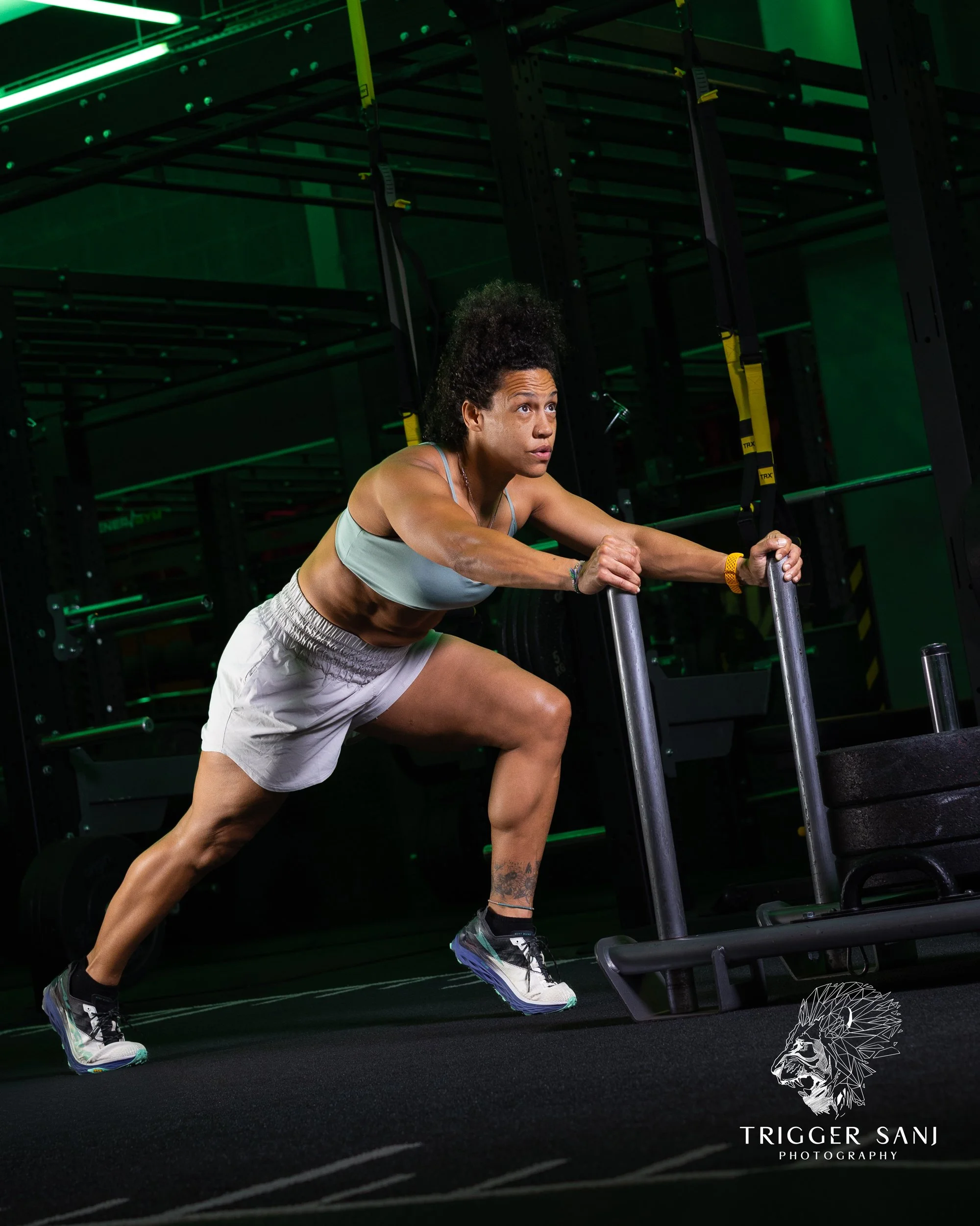 Female personal trainer pushing weighted sled in a gym