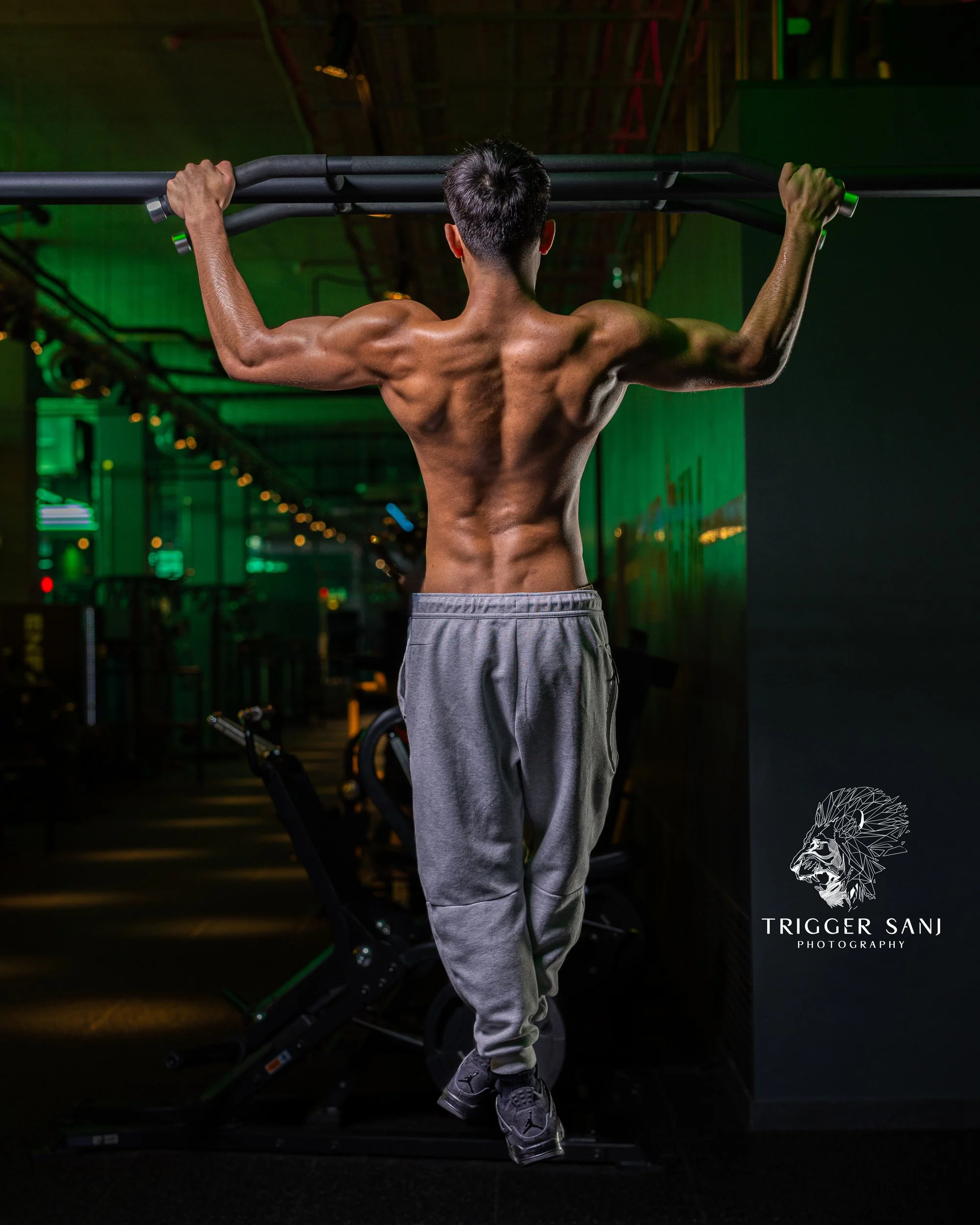 male personal trainer doing a pull up in a gym