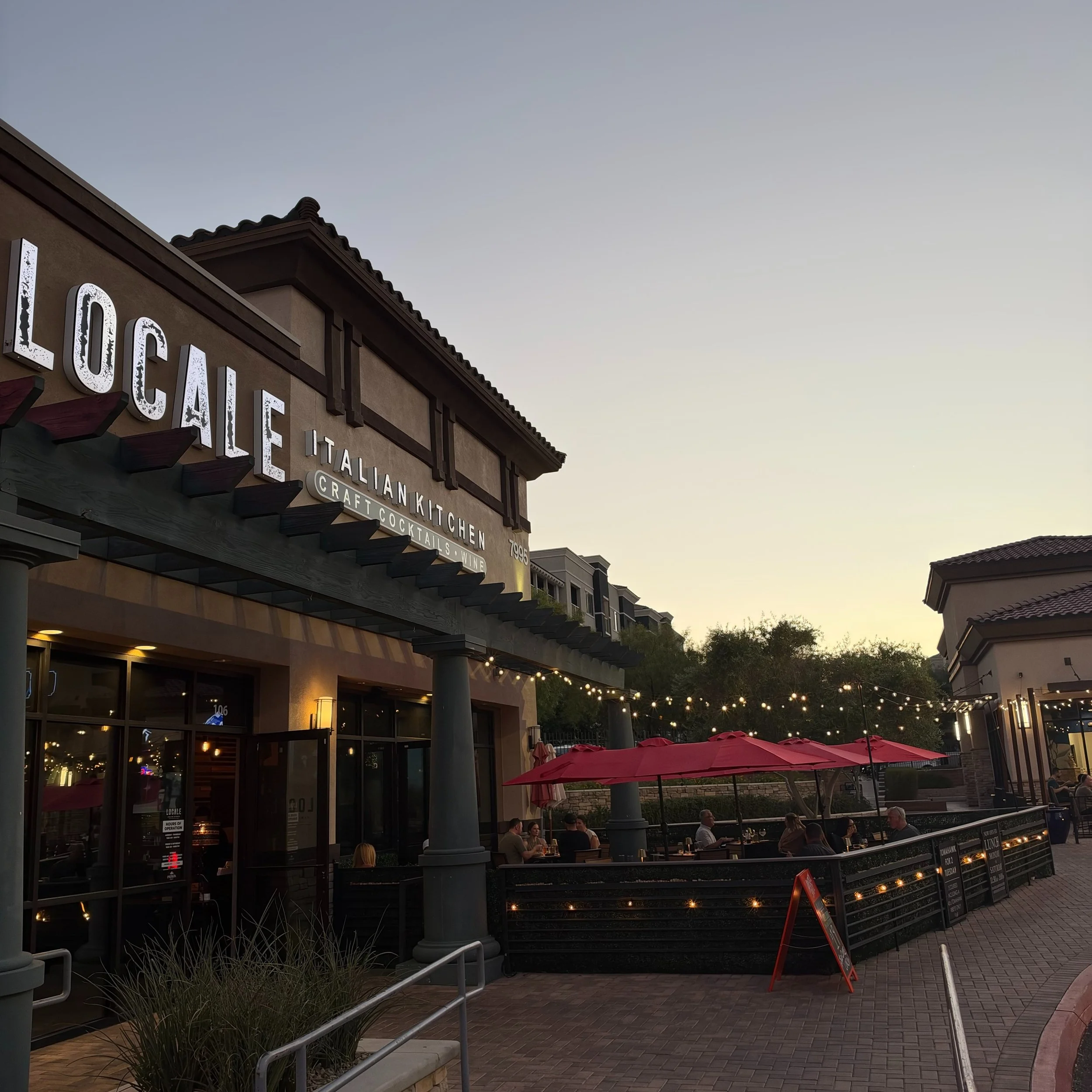 Evening on the patio at Locale. Red umbrellas, string lights, and the soft glow of dusk set the scene for Italian cooking done the Las Vegas way. Whether you&rsquo;re here for house-made pastas, a Tomahawk, or just a glass of wine outside, enjoy with