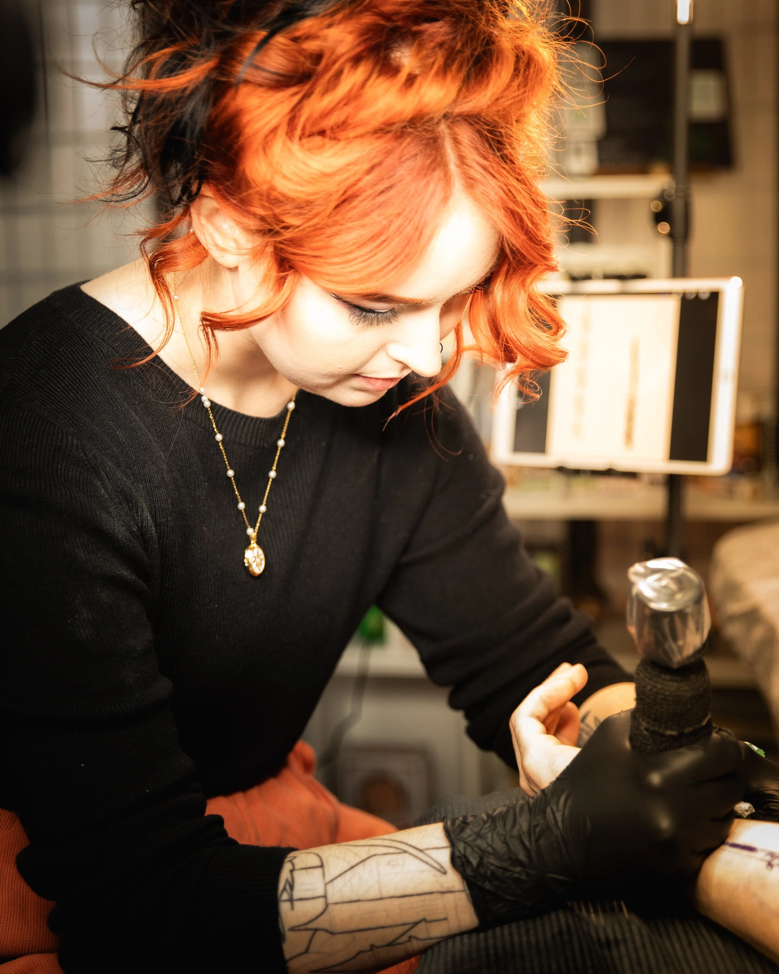a female tattoo artists tattoos a client.