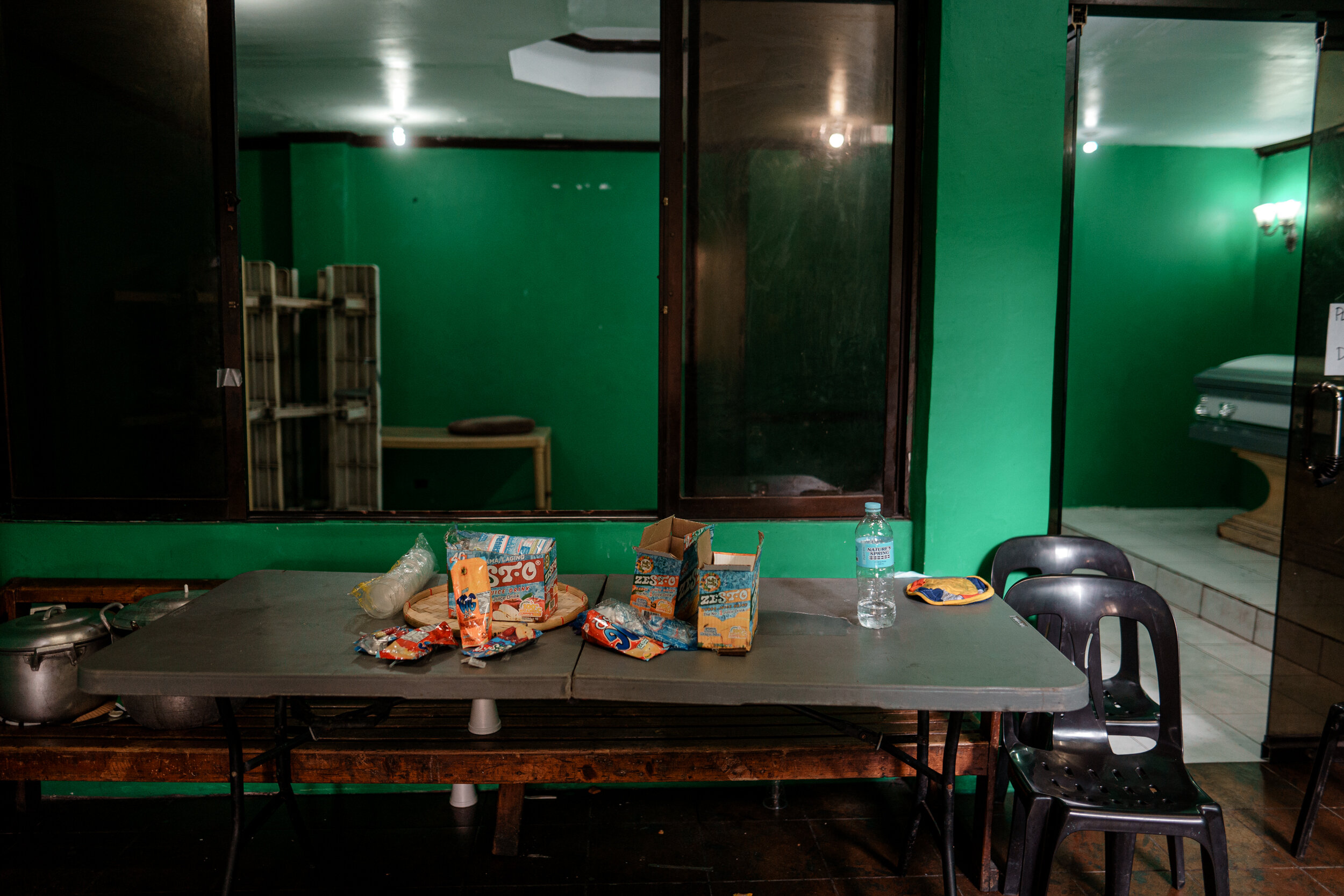  Empty bottles of beer, scrunched up bags of chips, and leftover Tetrapaks of juice scattered around. At the end of the room was a lone closed casket. No sign. No flowers. No one around. 