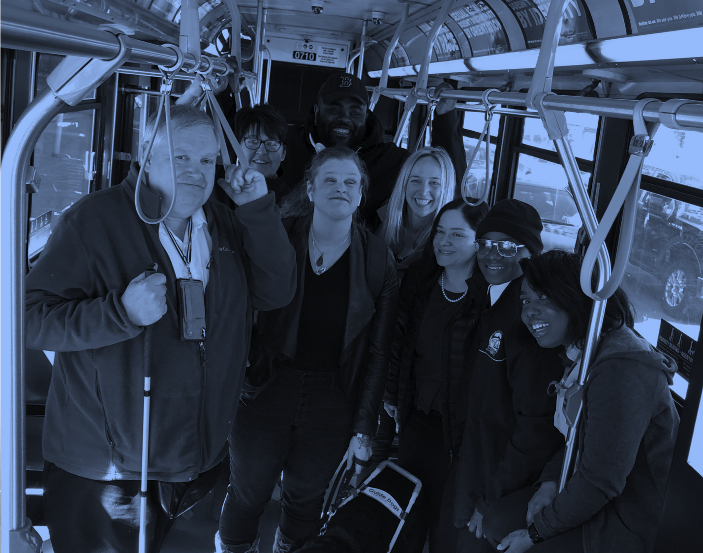 Group of eight people on an MBTA bus smiling with a black dog. The people in the photo worked hard to transform the idea of Access AI into reality. Thanks to all!