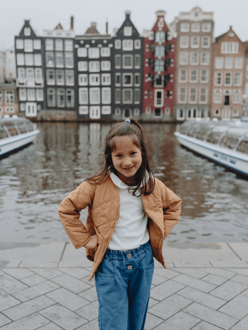 Family Photoshoot in Amsterdam by Vicky McLachlan Photography - American Family with a little girl standing in front of Damrak in Amsterdam with Dutch buildings and boats in the background-1.png