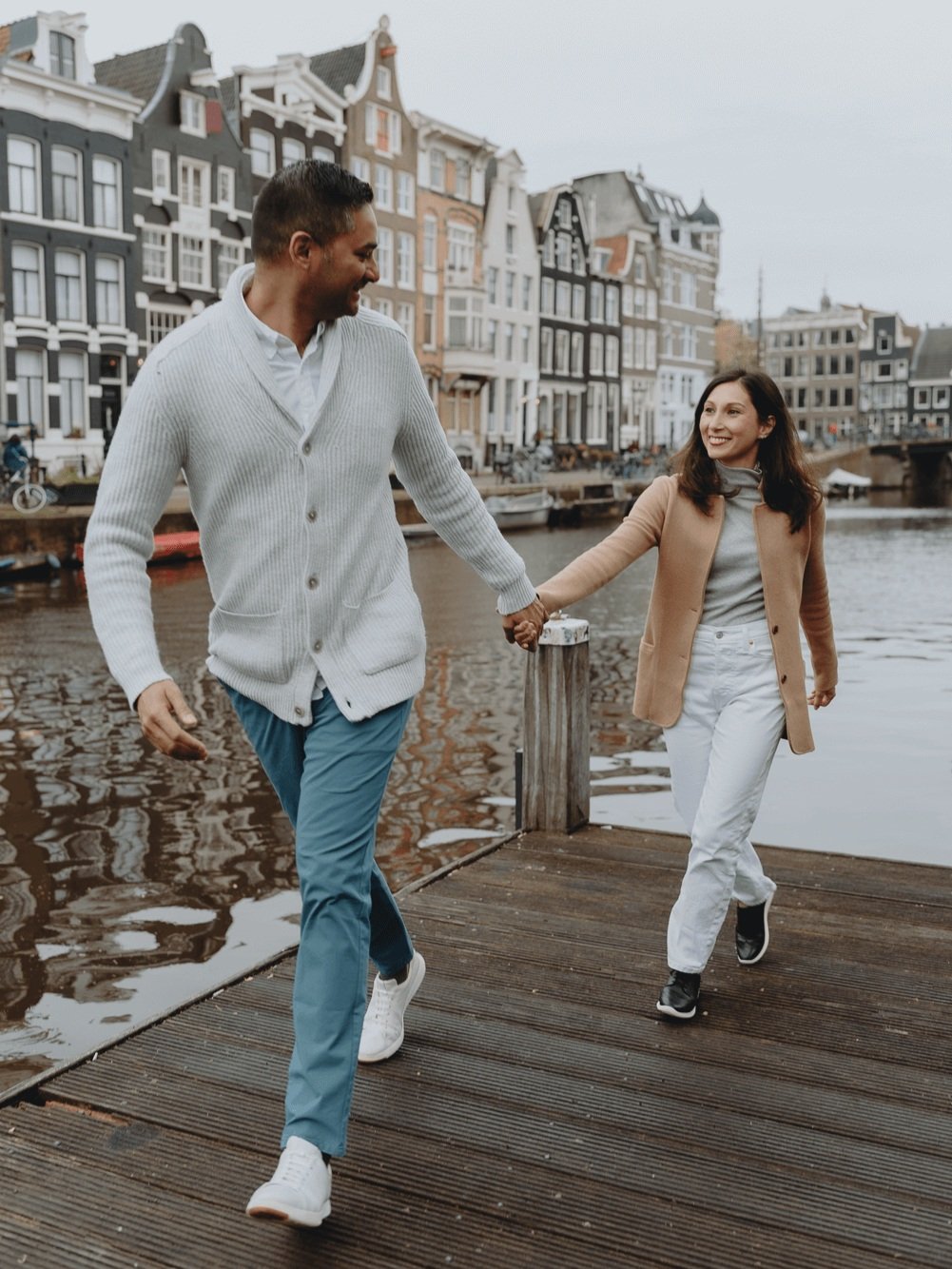 Family Photoshoot in Amsterdam by Vicky McLachlan Photography - American Family with husband and wife running together while holding hands on a dock next to a Dutch canal-1.png