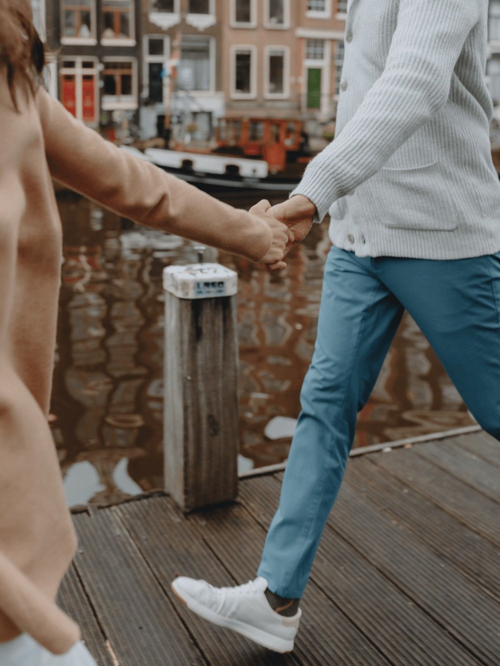 Family Photoshoot in Amsterdam by Vicky McLachlan Photography - American Family with husband and wife running together while holding hands on a dock next to a Dutch canal_2-1.png