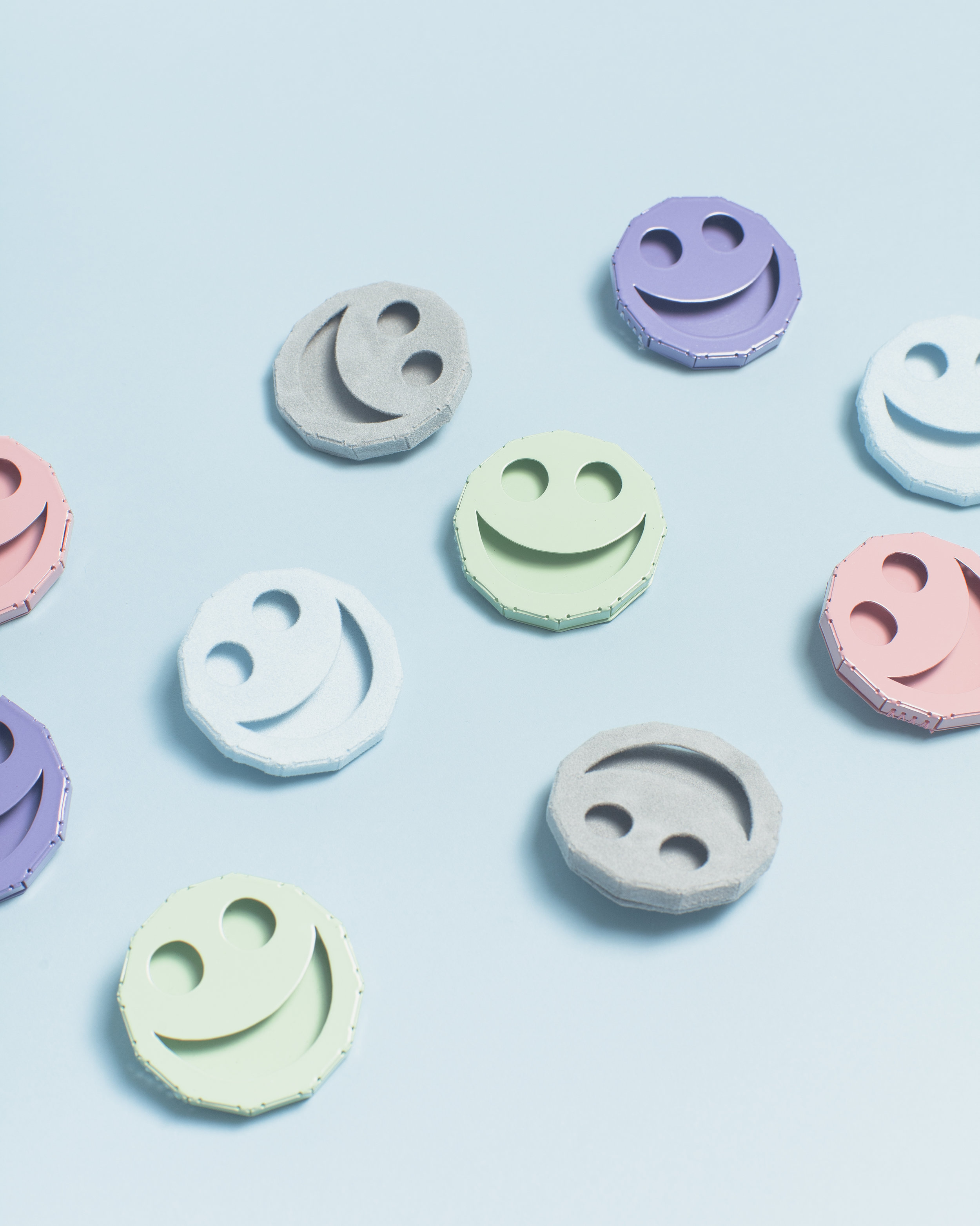   Fuzzy Smile Symbol Pins   Brass, Nickel, Paint, Flocking  2”x2”x.5”  (Baby Blue, Light Grey)     Smile Symbol Pins   Powder-Coated Brass, Nickel  2”x2”x.5”  (Mint Green, Pastel Purple, Pastel Pink)    Photo by Harry Gould Harvey 