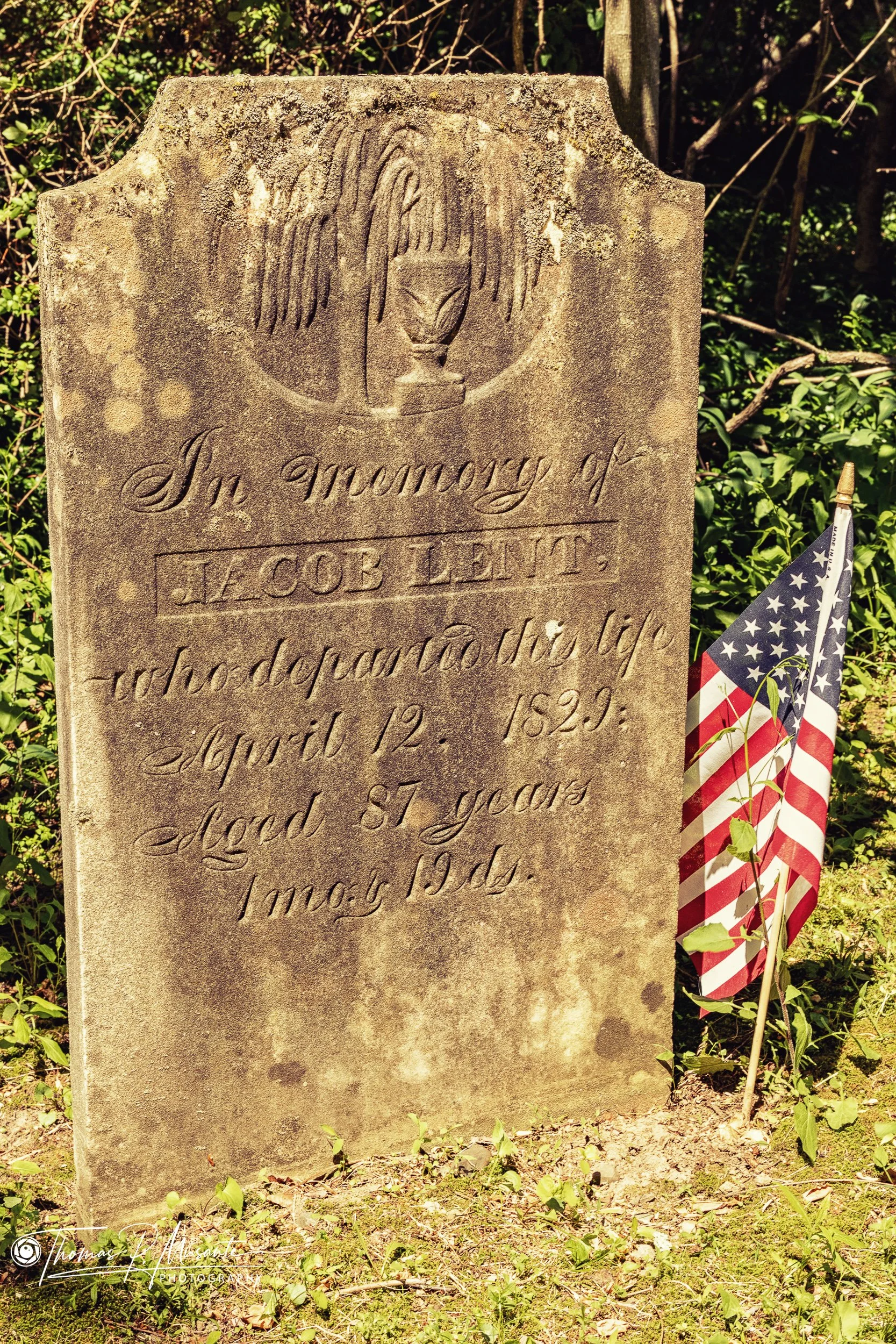 Jacob Lent's 1829 gravestone with a small flag, Tomahawk Chapel.
