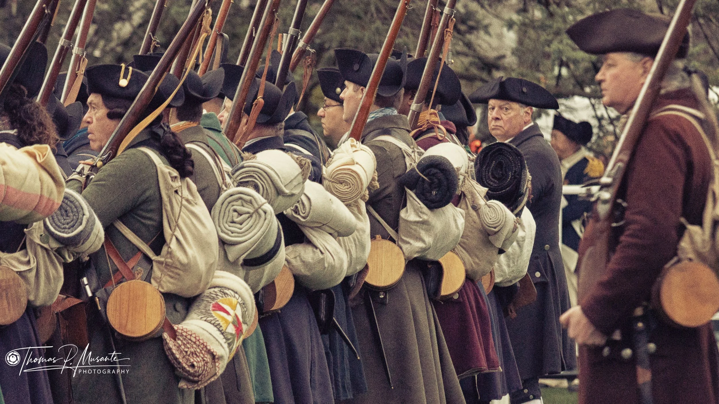 Rank of reenactors with shouldered muskets in cocked hats, Lexington.