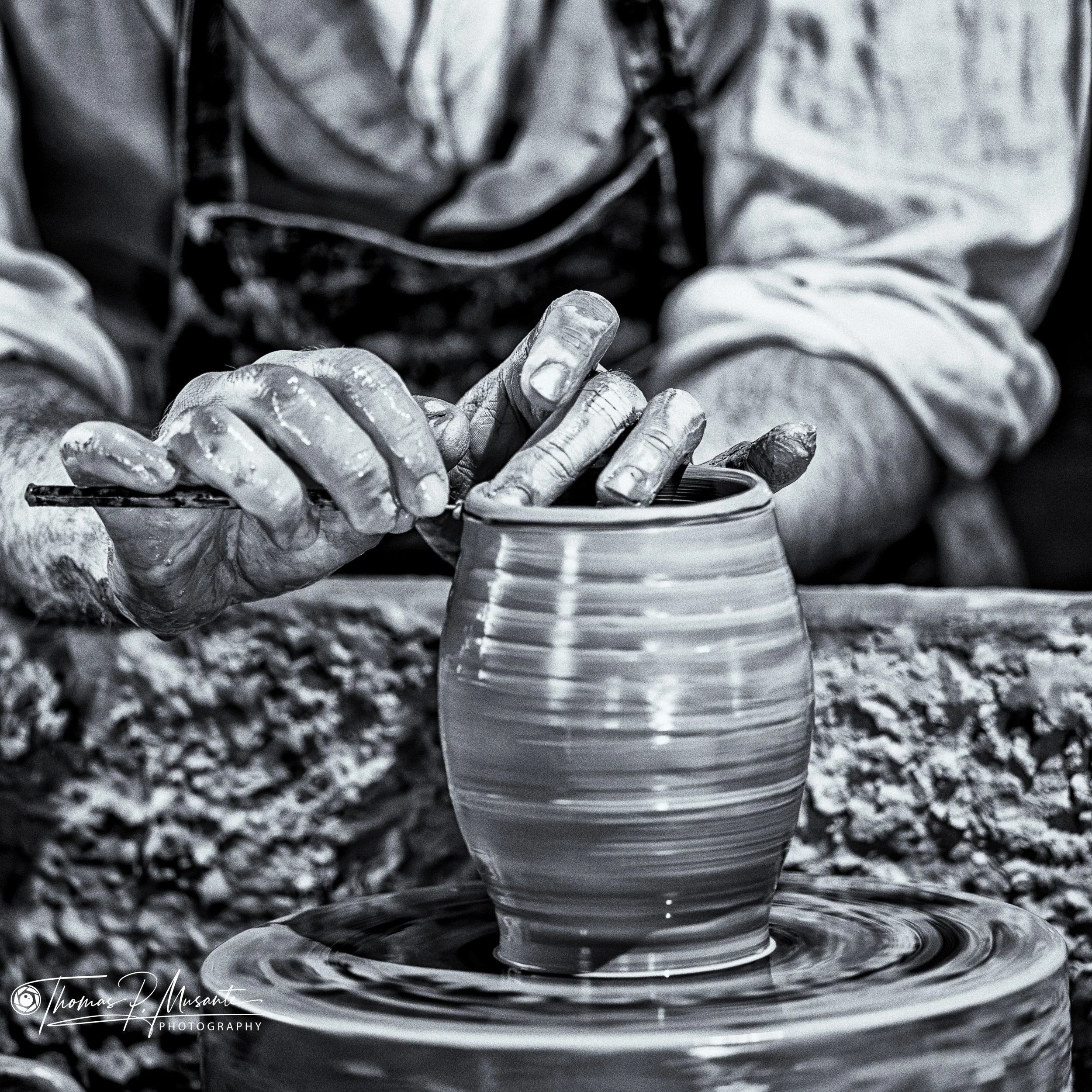 Potter's clay-covered hands at the rim of a jar on the wheel, Old Sturbridge Village.