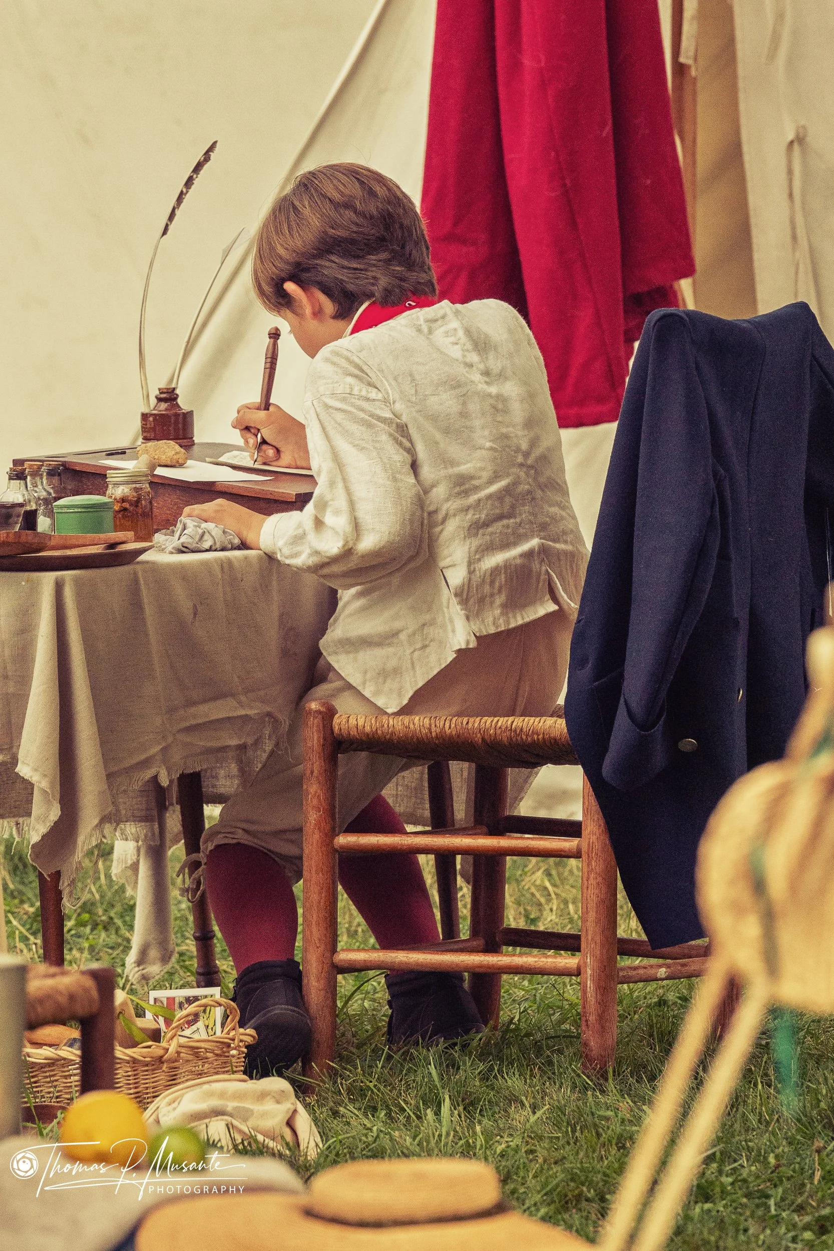 A Boy Writing at a Camp Desk Under Canvas