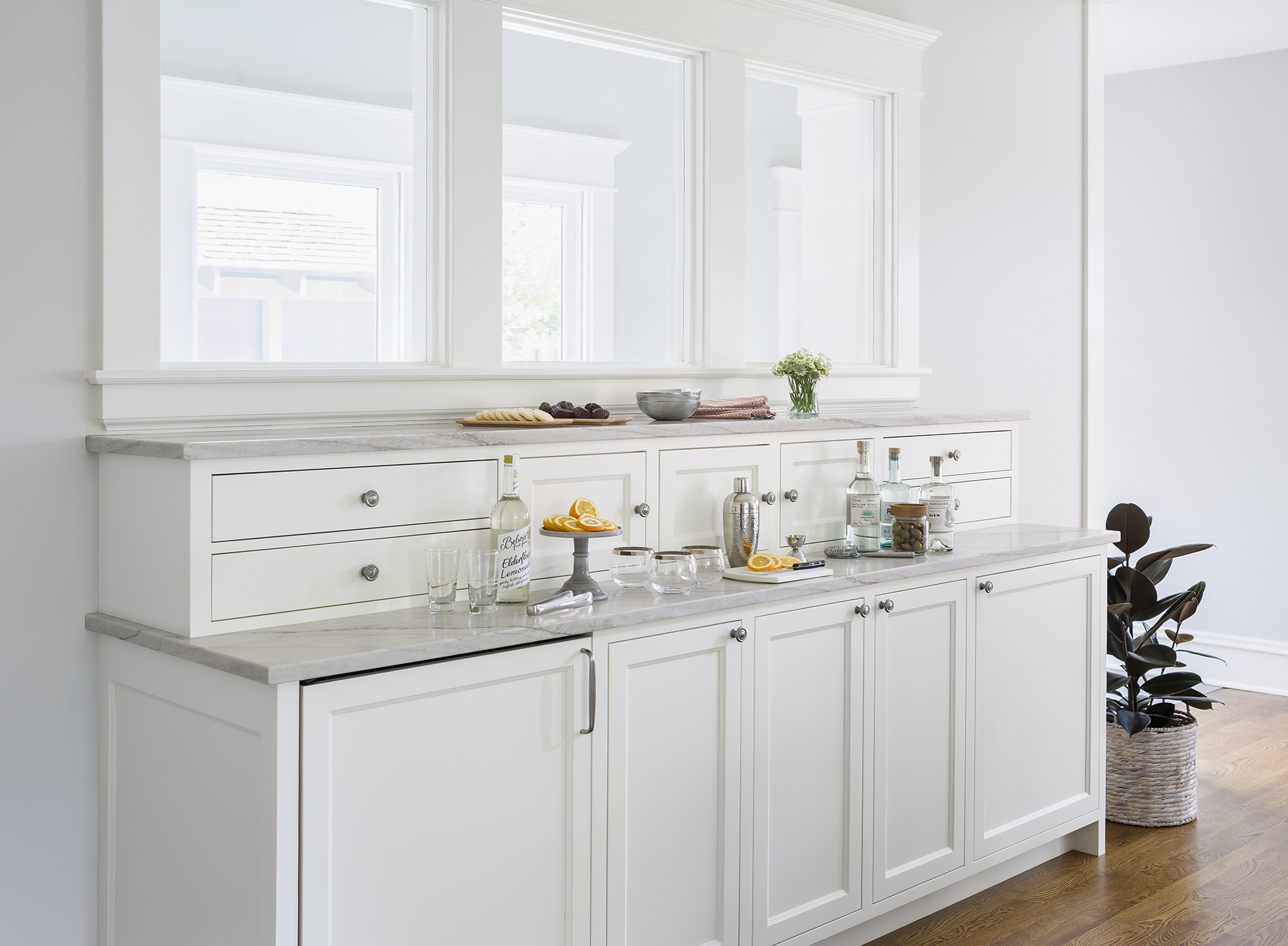 This stunning custom-designed hutch acts as both a serving buffet and bar and contains a beverage fridge below. The three small doors at the top hide charging stations for the family’s electronic devices. The interior windows look out to a mudroom and let in more natural light.