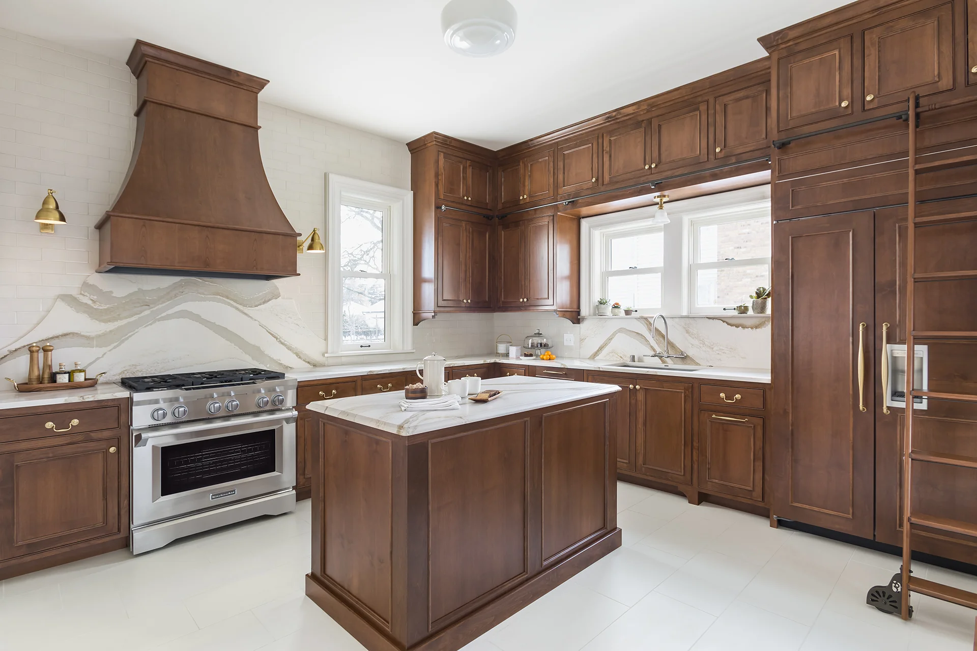 Light-colored floors and backsplash contrast with the darker-stained cabinetry.