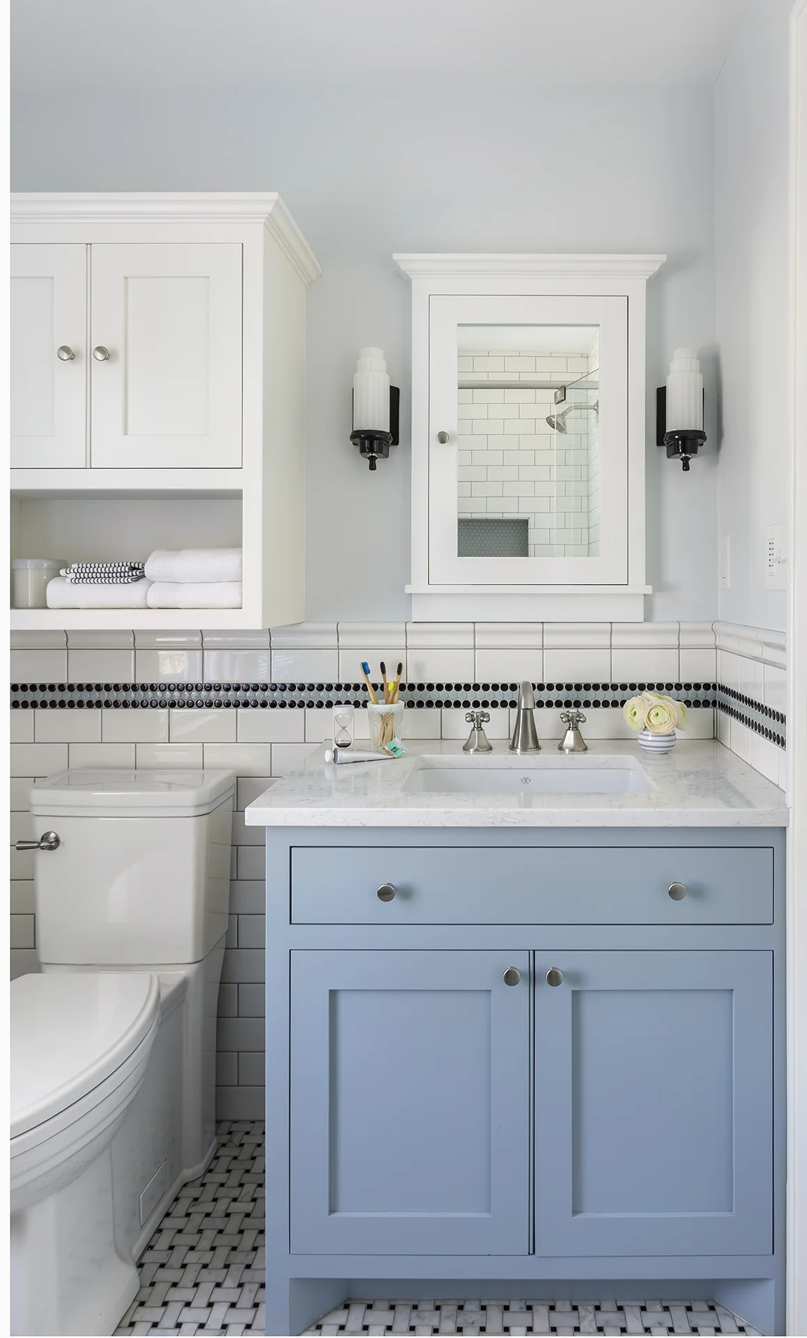Reconfiguring the room and capturing space from an adjacent closet allowed room for custom cabinetry and additional storage. Period details - such as subway and basketweave tile - marry the brand new space with the historic home.
