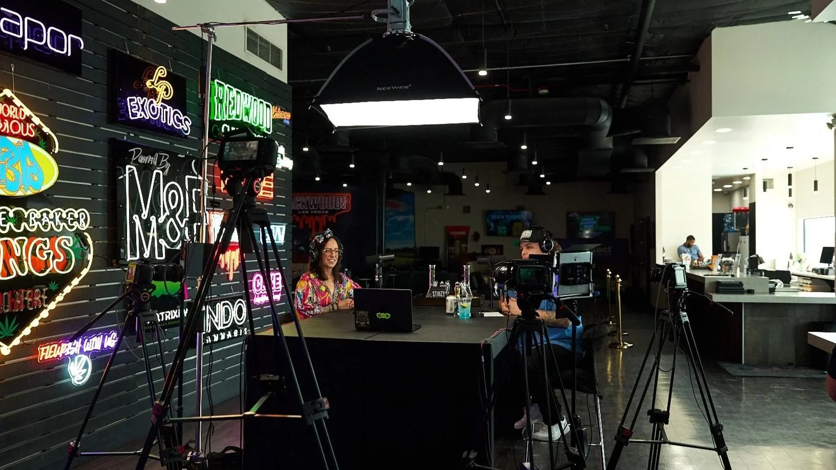 Wide view of the NuWu Sessions Podcast recording setup inside Sky High Lounge at NuWu Main Dispensary in downtown Las Vegas, showing cameras, studio lighting, and neon cannabis brand signage.