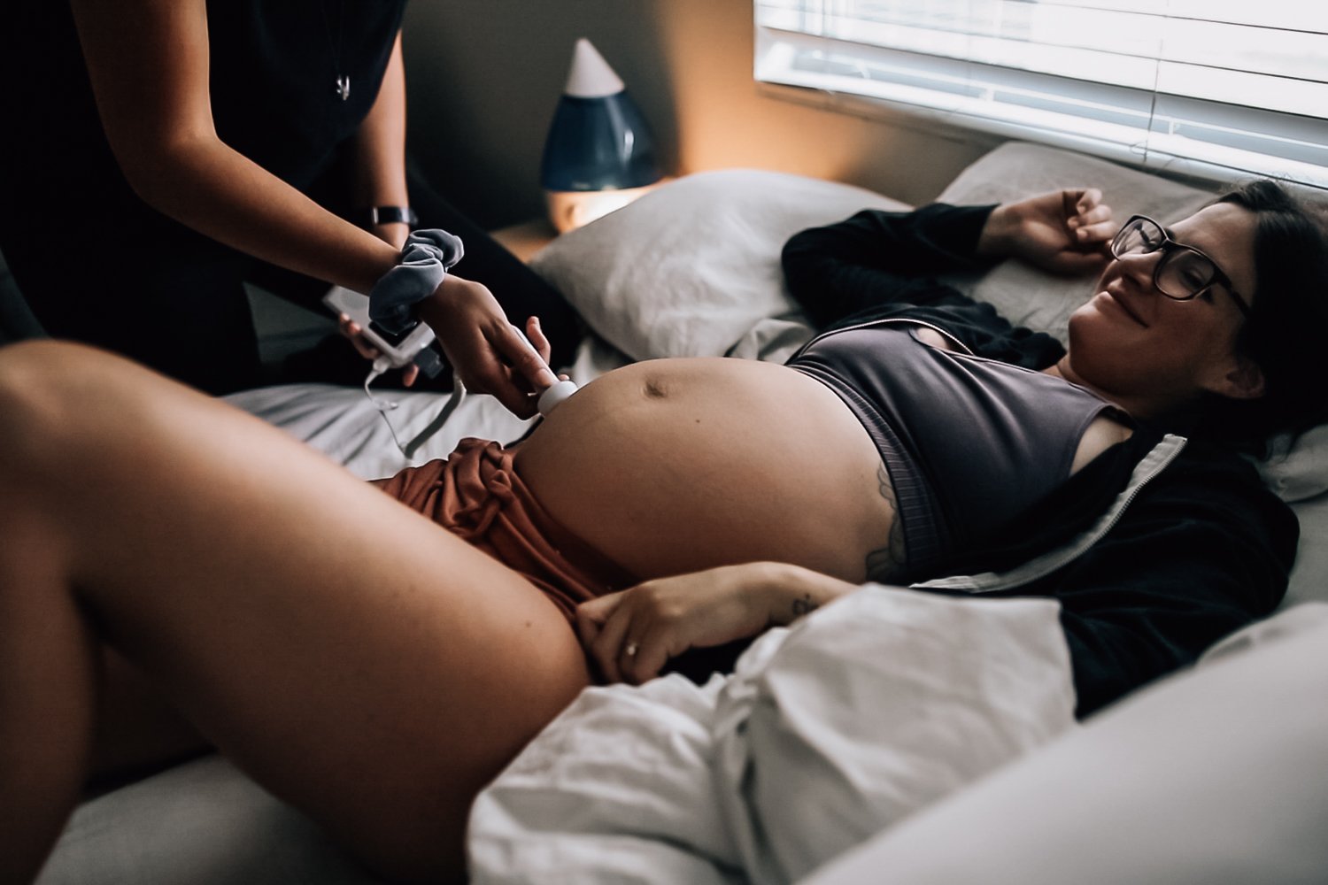 A woman lying on a bed receiving an ultrasound exam from a healthcare professional.
