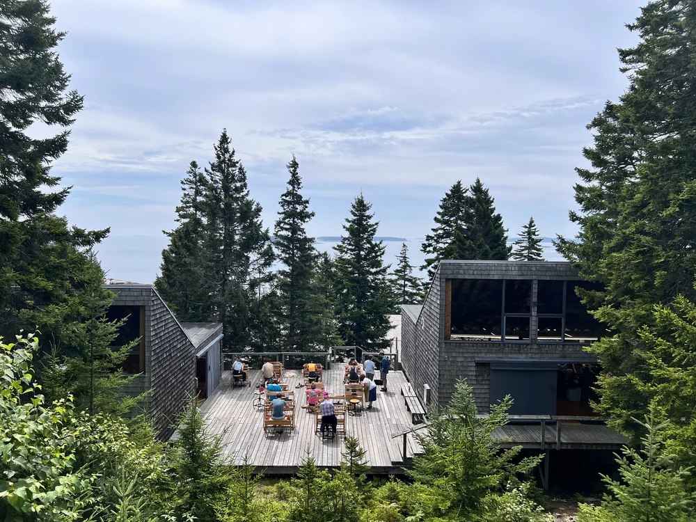 Students move their looms onto the deck outside the Fiber studio to enjoy the sunshine on the Haystack campus, 2023. Image courtesy of Haystack Mountain School of Crafts.