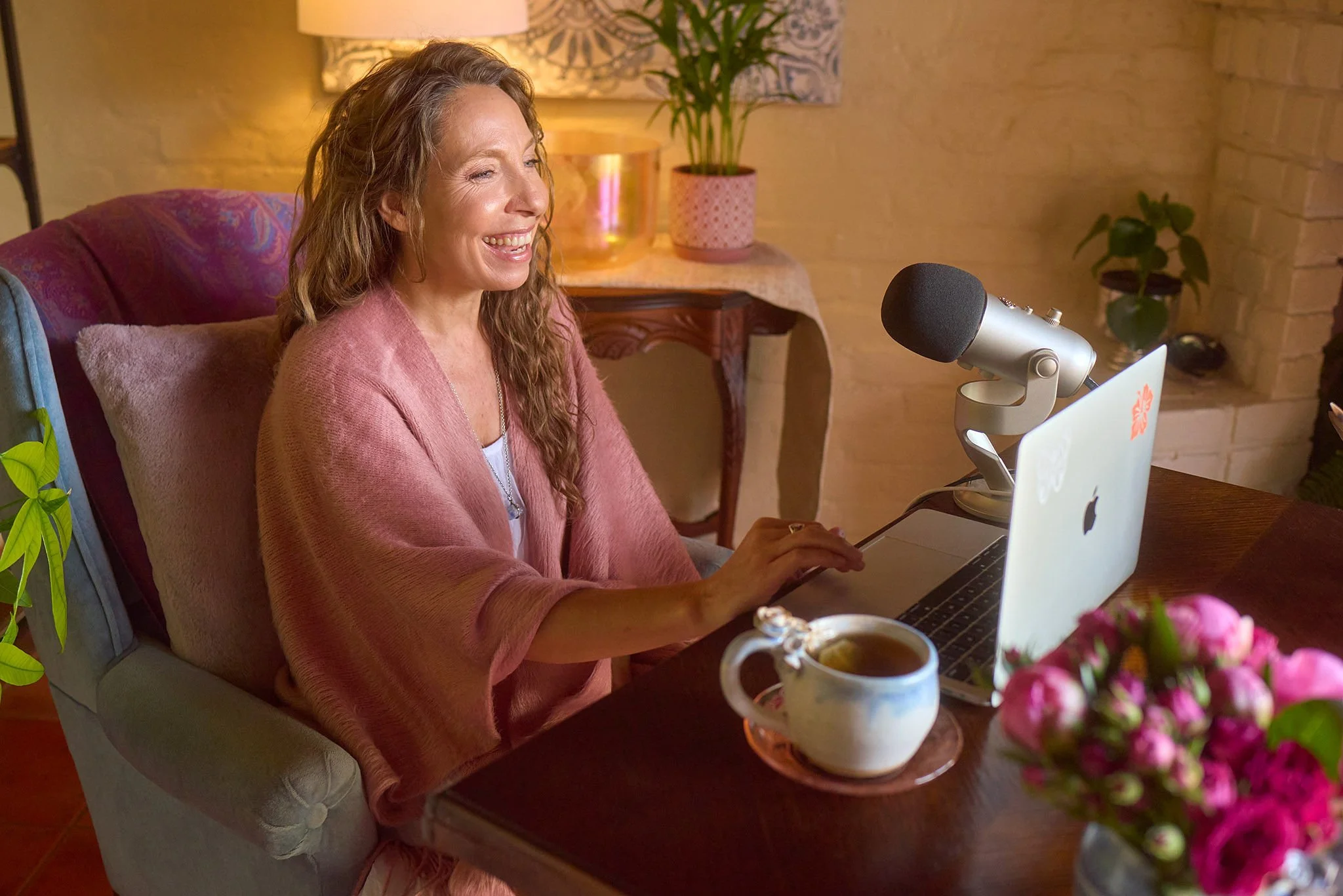 Amala Rose, Somatic Experiencing Practitioner, ascension guide, energy healing, sound healing, therapeutic arts therapy, smiling, on Zoom working with a client from cozy office in Tucson & Sedona AZ, with a laptop for online sessions