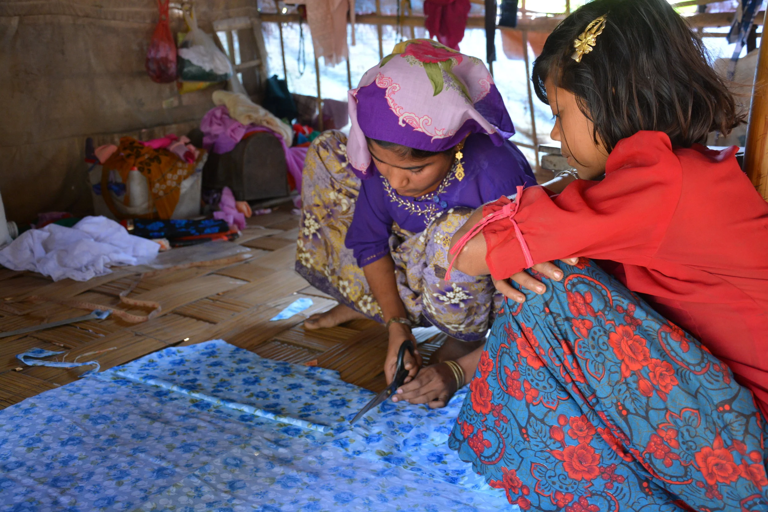 Daw Swe’s daughters cutting cloth for her to sew shirts.