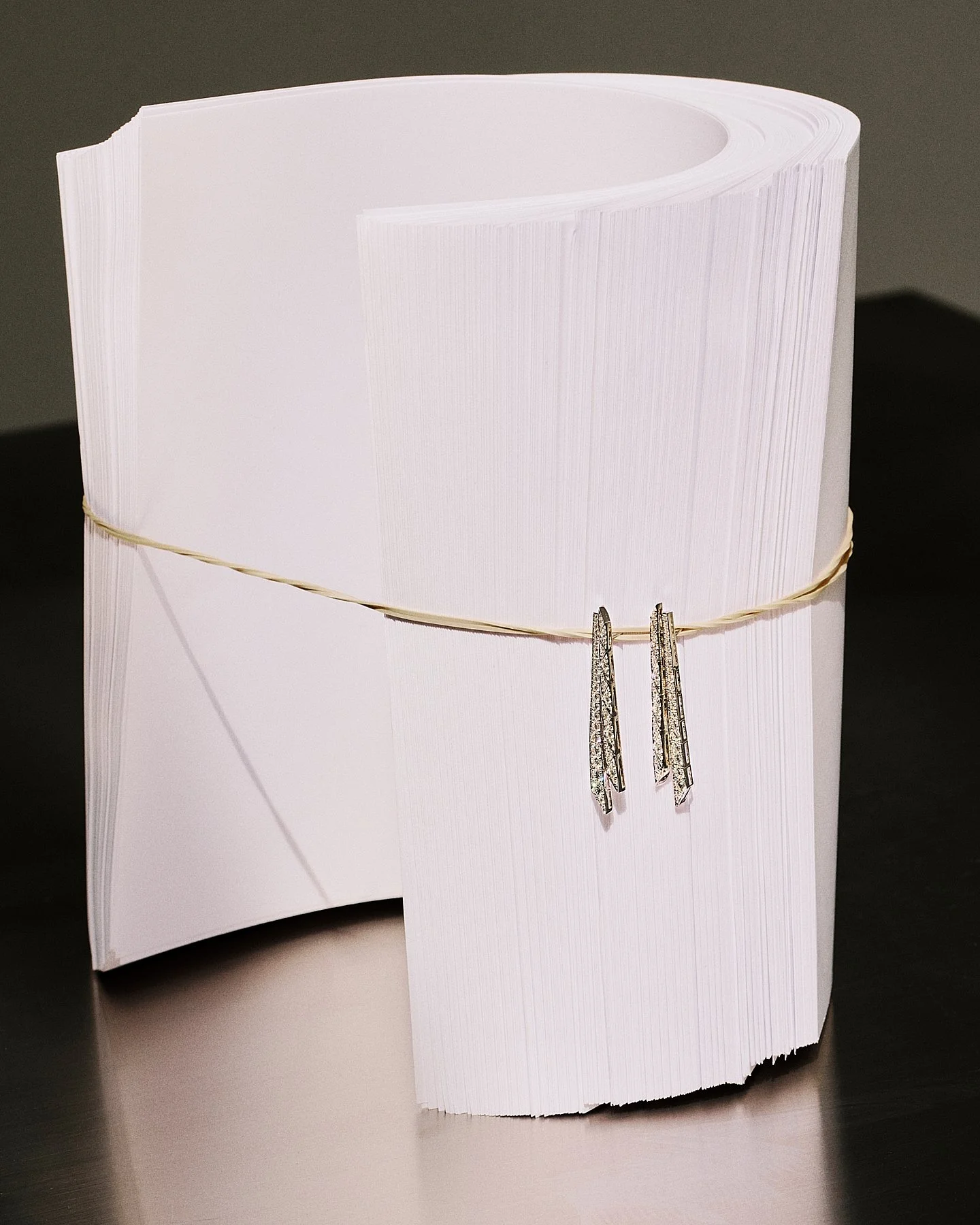 A pair of silver earrings with geometric designs hanging on a white paper display.