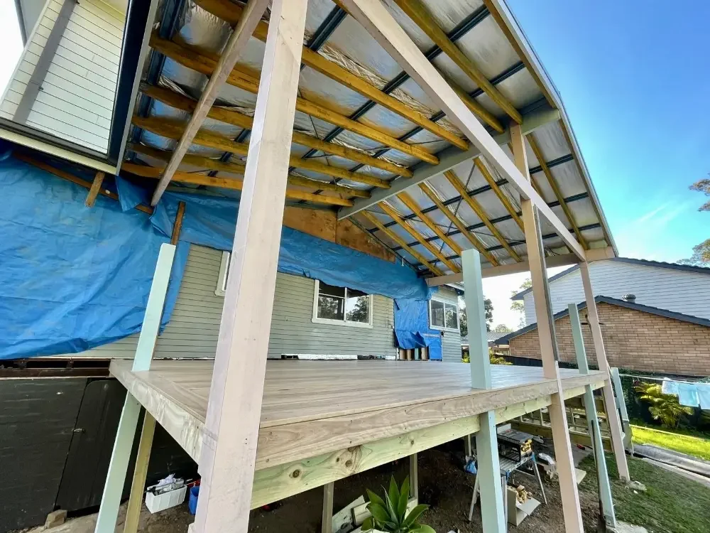 Elevated timber deck under construction with covered patio roof.