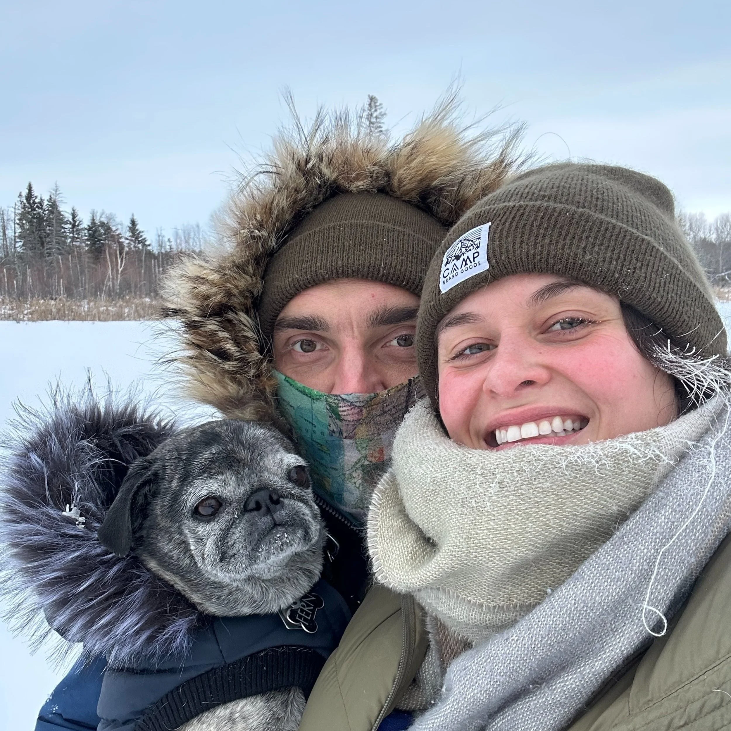 A picture of Jarrett, Eryn and their pug Fern bundled up for winter