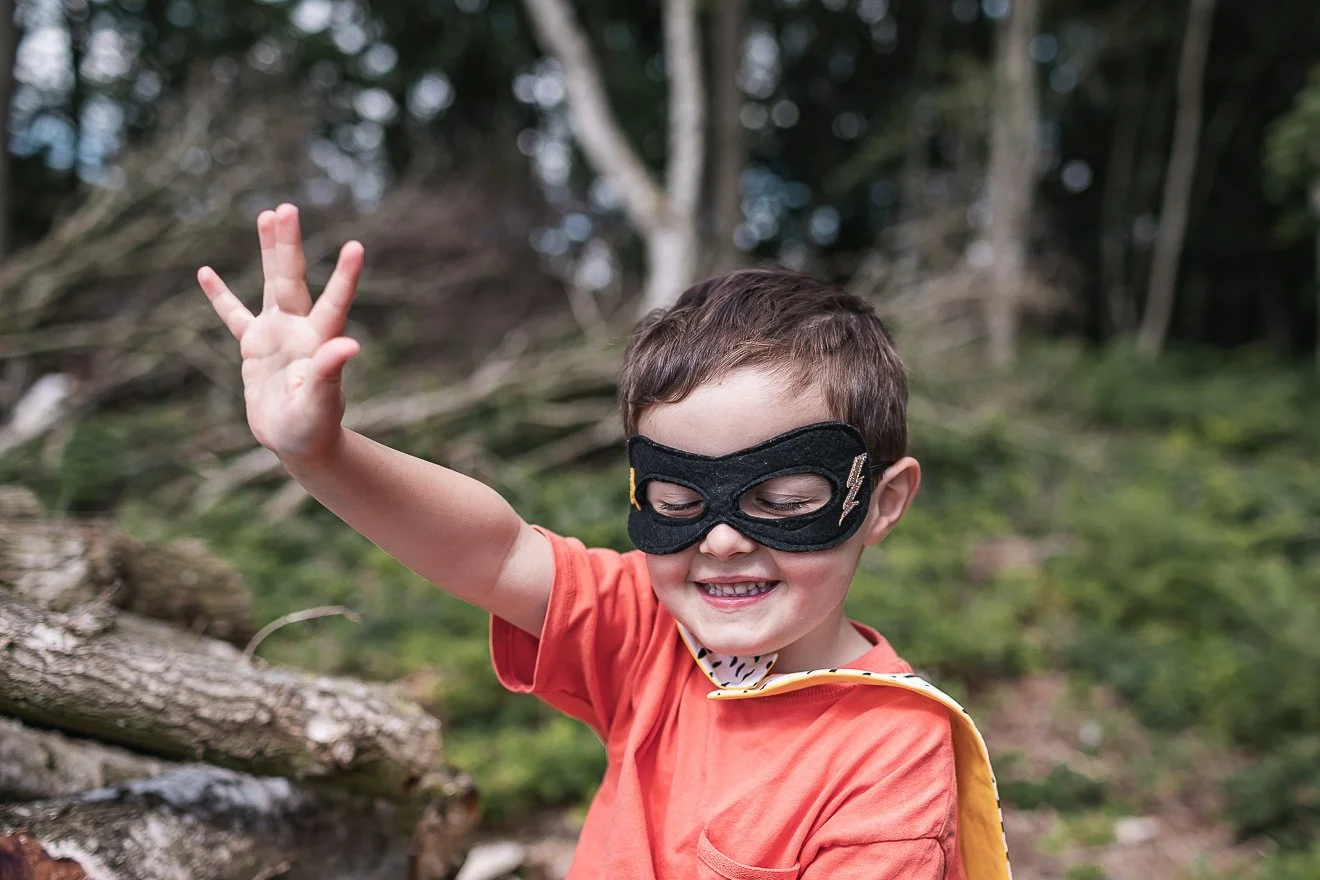 Boy imagining he has super powers wearing superhero mask and cape (Copy)