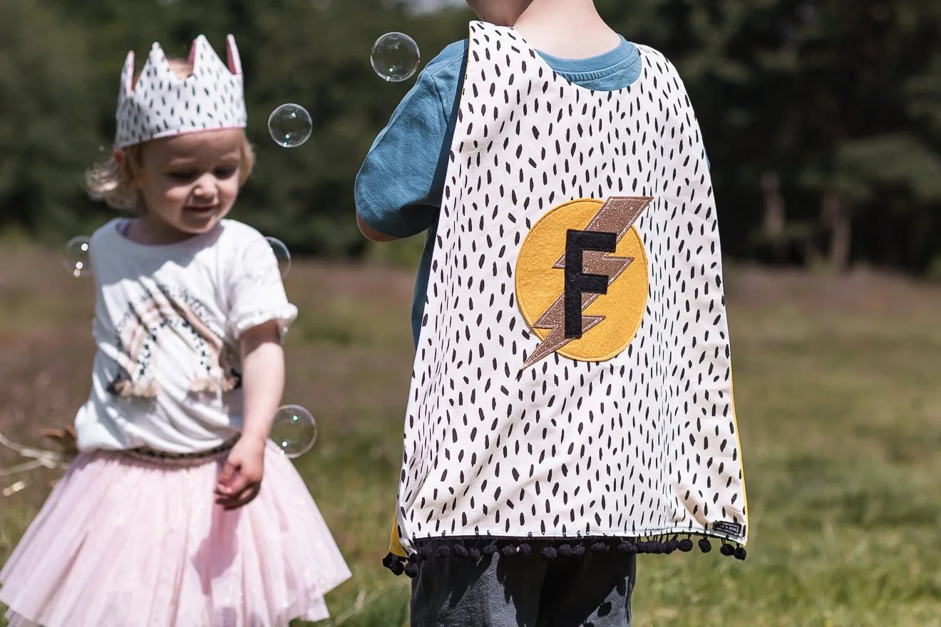 Two young superheroes playing outdoors in their personalised capes.