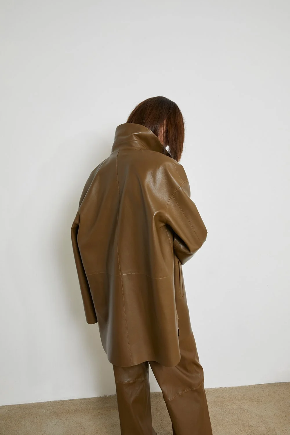 Fashion creative direction with tonal brown leather look and back-view studio composition.
