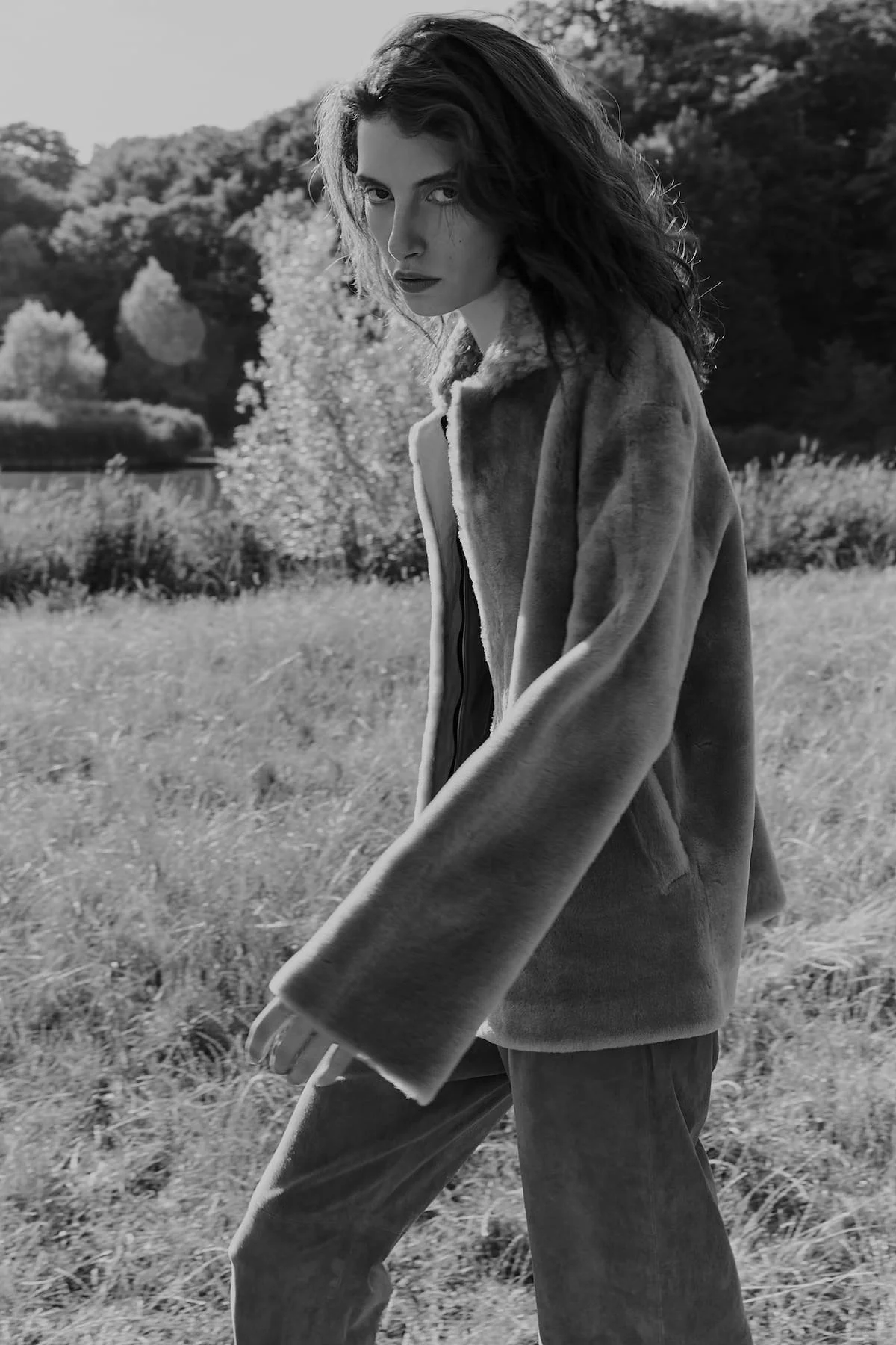 Black and white outdoor fashion editorial with sustainable shearling coat and natural landscape.