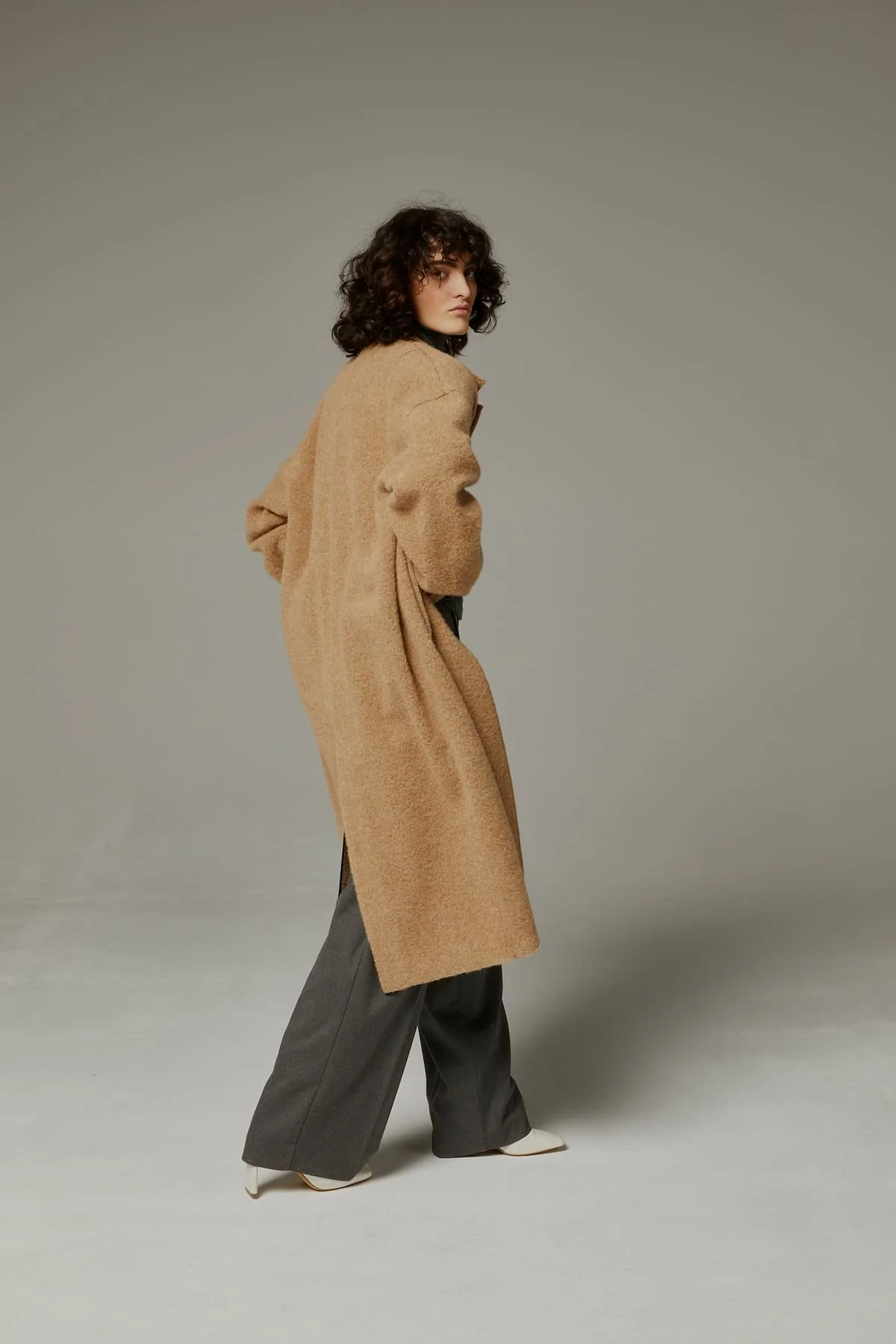 Luxury fashion editorial with beige long coat, soft tailoring and minimalist studio direction.