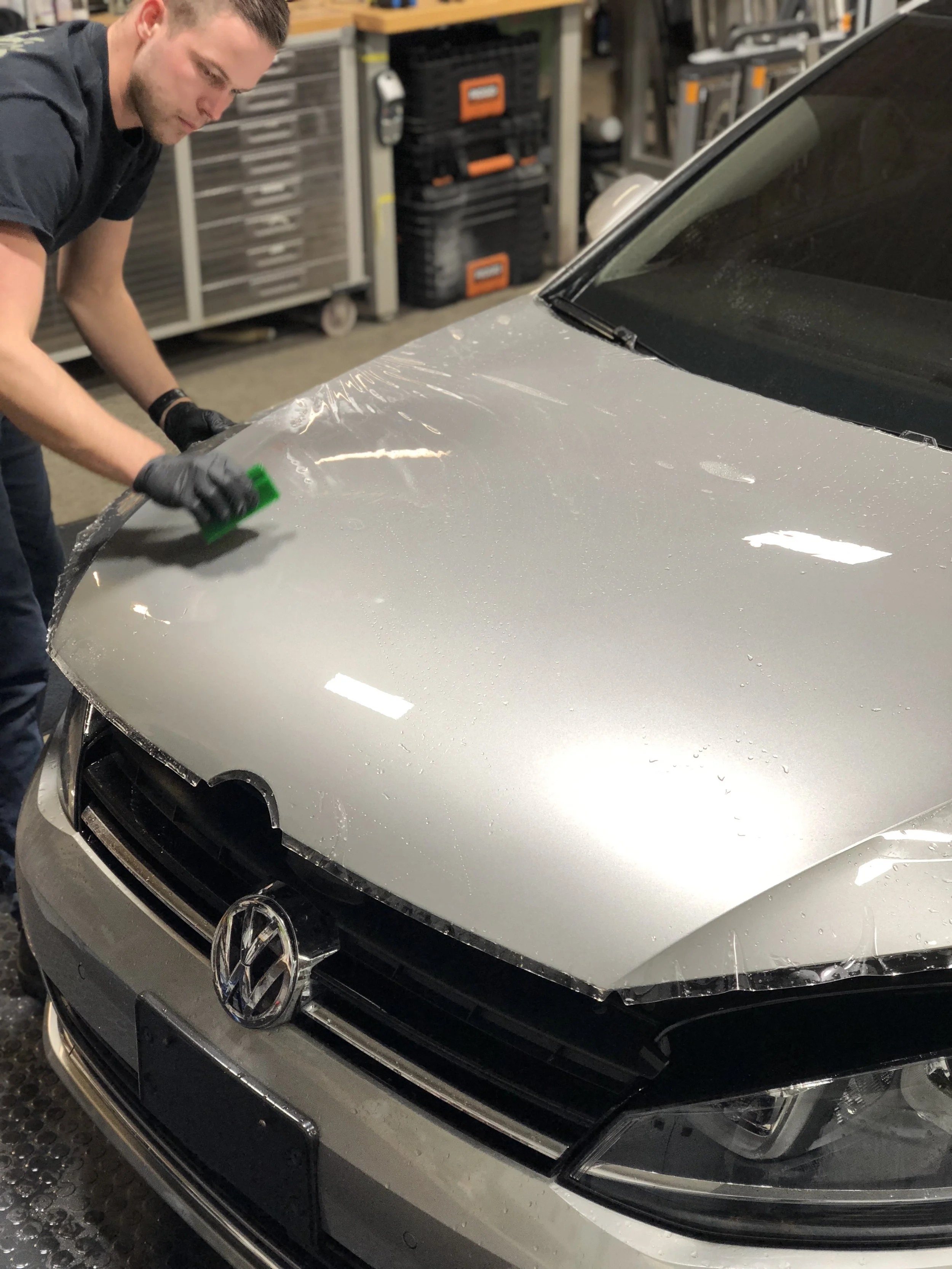 Installer using squeegee to remove installation solution under neath the film - this bonds the film to the body panel.