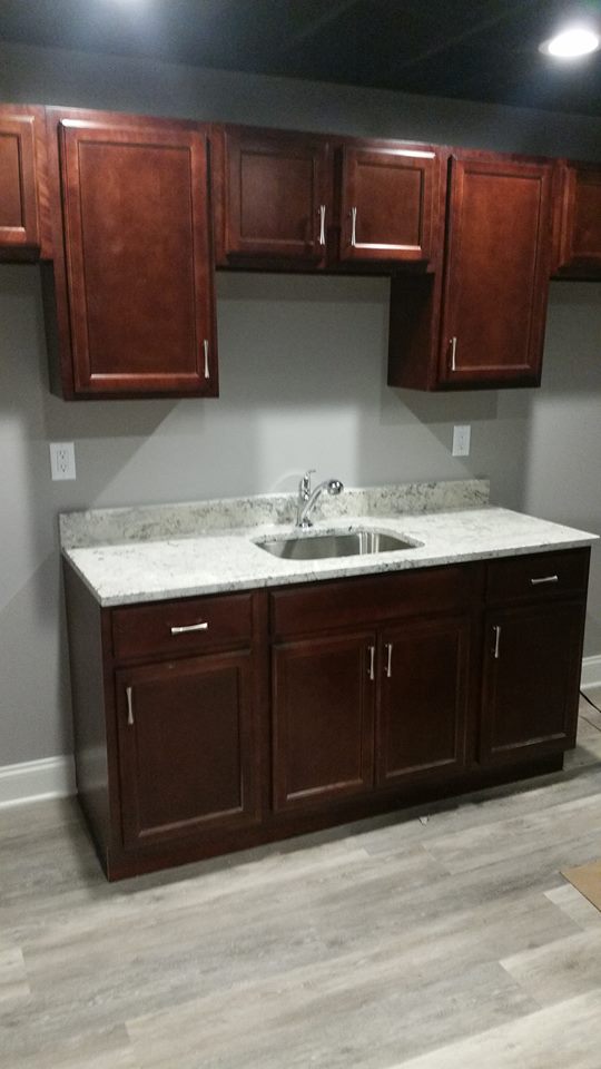 New dark wood cabinets over matching cabinets with a light-colored counter top and a sink.