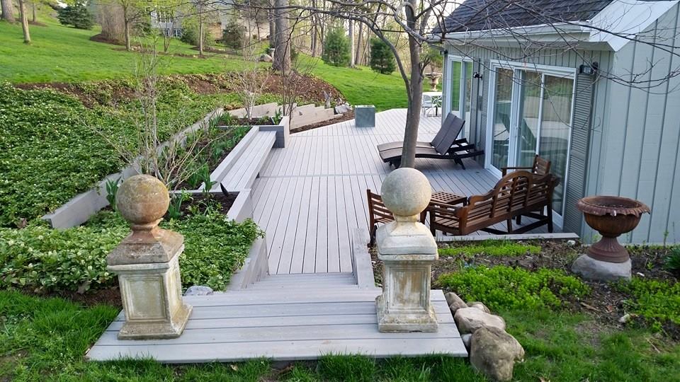 A pair of stone pillars at the top step of a small wrap-around deck.