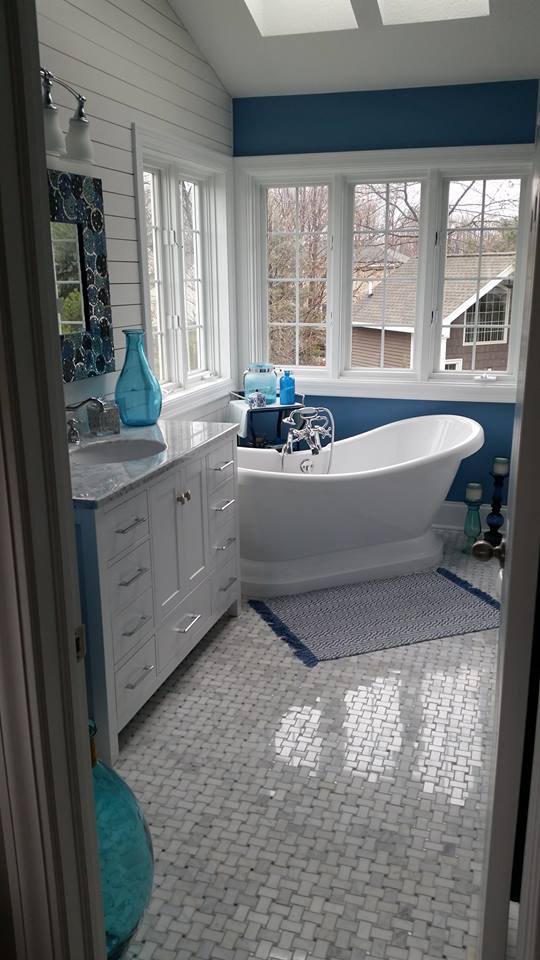 A new white bathroom with a soaker tub, and a dark blue accent wall.